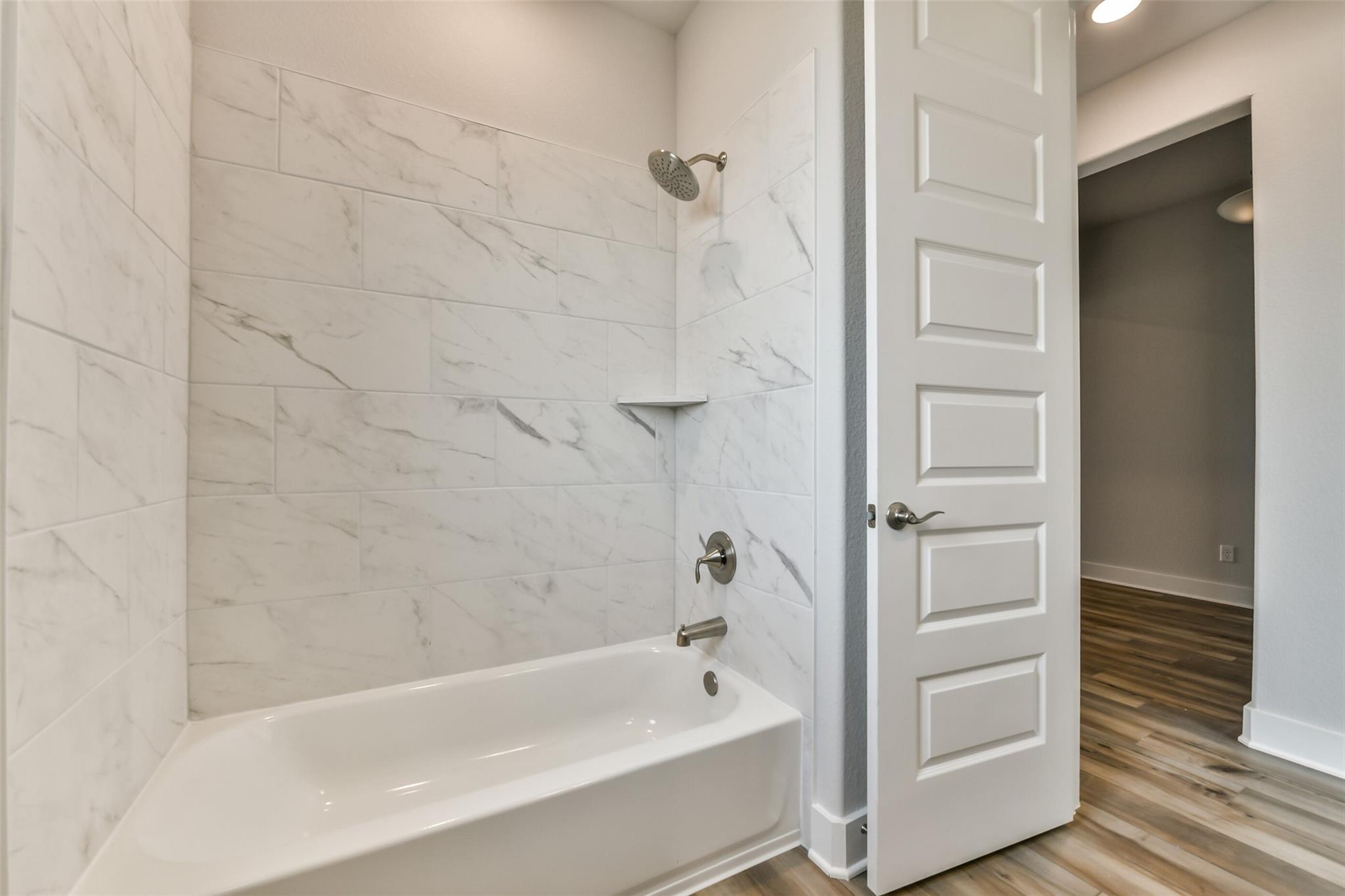 Luxurious master bathroom with white subway tile shower, soaking tub, and glass enclosure in Davidson Homes The George A, Lago Mar, Texas City