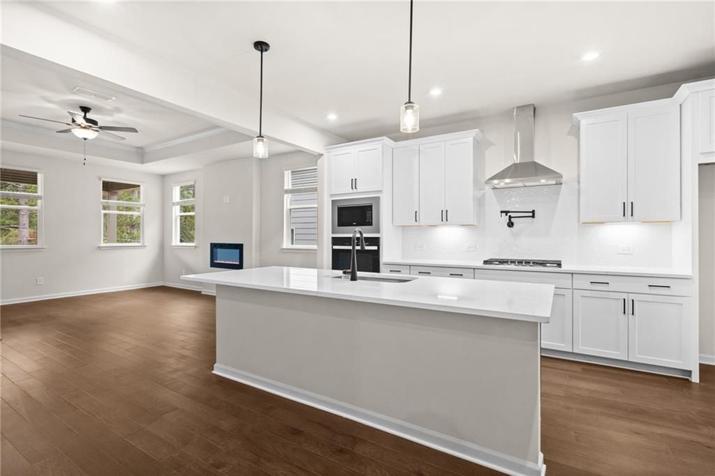 Modern open-concept kitchen with white island, stainless steel appliances, and hardwood floors in The Glenwood A, Loganville, GA