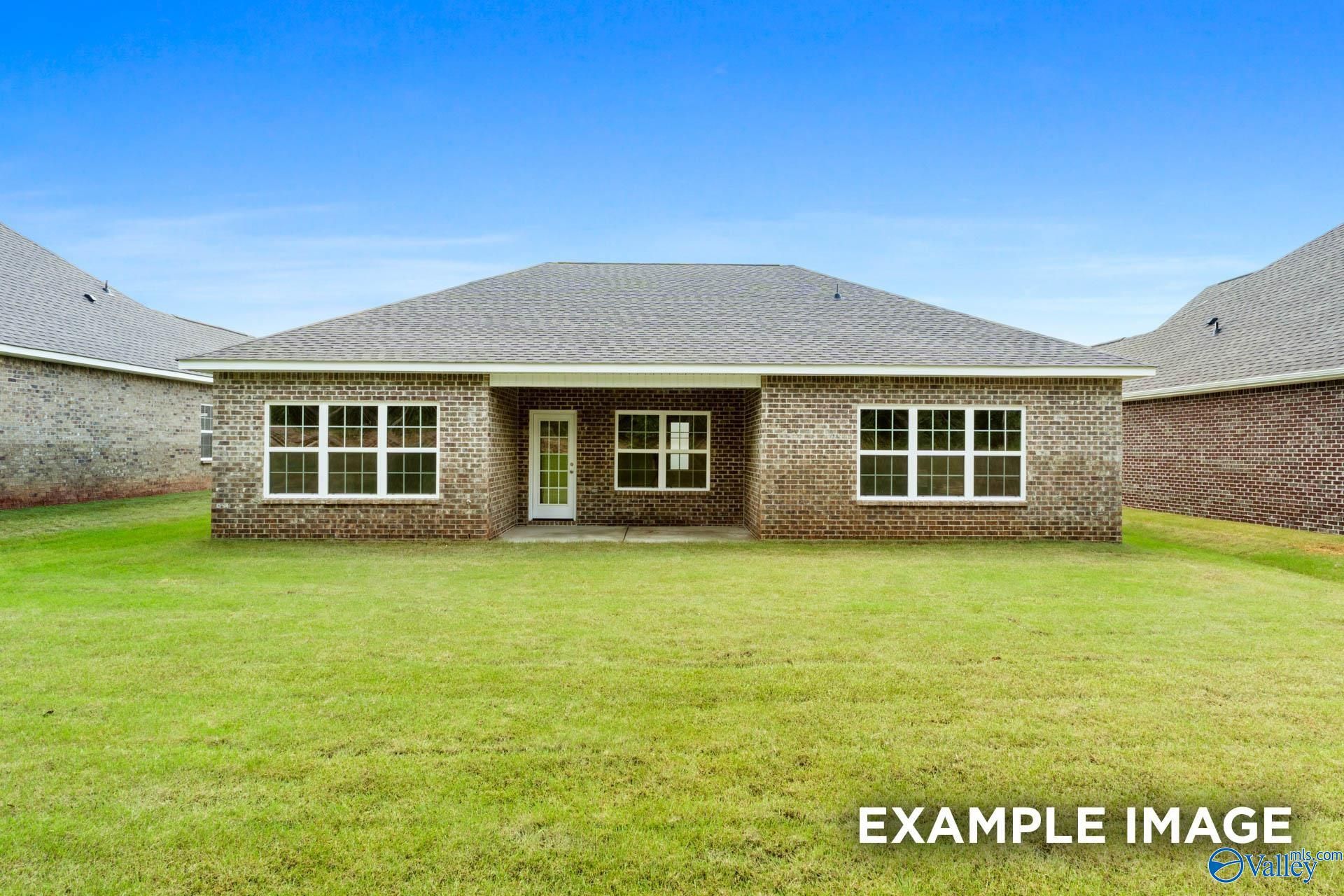 Brick back exterior of The Montgomery 3-bedroom home with covered patio, large windows, and green lawn in Pikes Ridge, Meridianville, Alabama