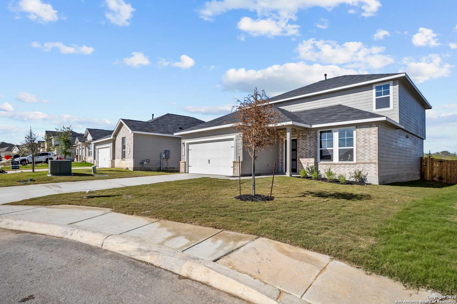 Modern 2-story tan brick home with 2-car garage, front porch, and landscaped yard in Horizon Pointe, Converse, Texas by Davidson Homes The Douglas B