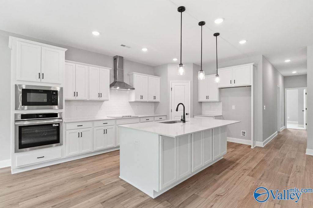 Modern gourmet kitchen with white cabinets, quartz island, and stainless steel appliances in The Rockford, Cain Park home.