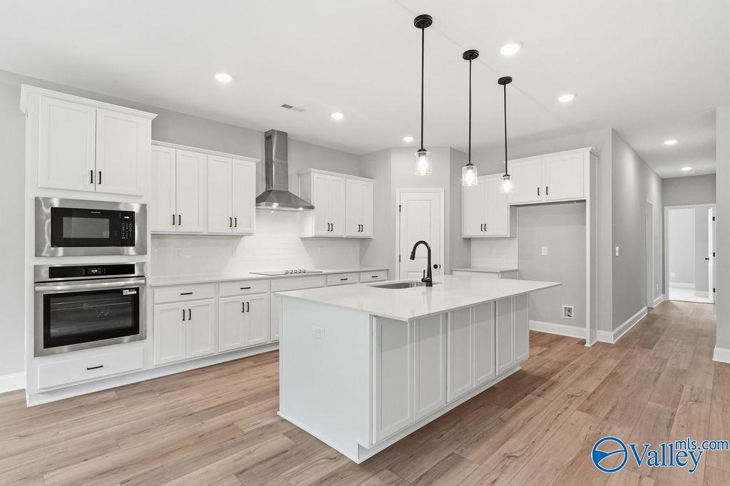 Modern gourmet kitchen with white cabinets, quartz island, and stainless steel appliances in The Rockford, Cain Park home.
