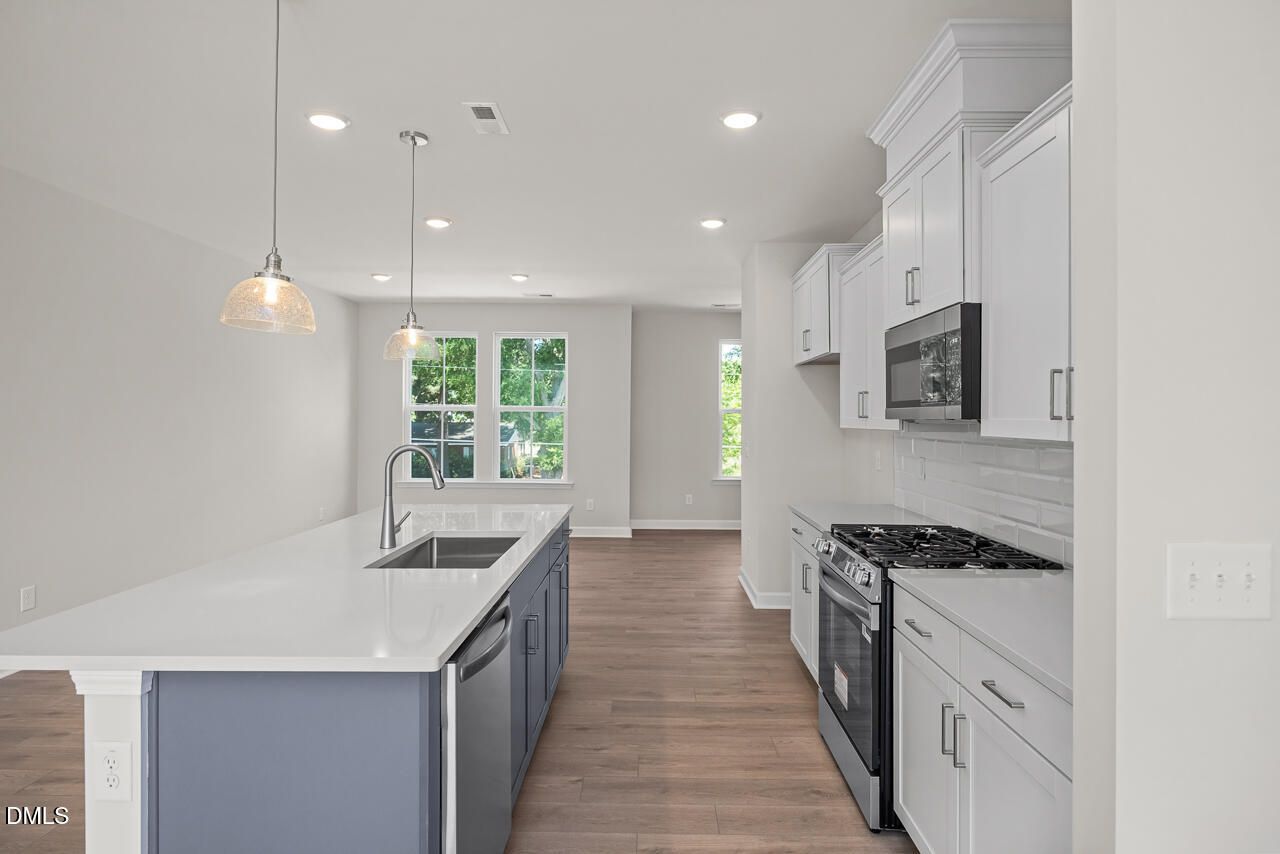 Modern kitchen with white cabinets, quartz island, and stainless appliances in The Mitchell floor plan at Camden Park.
