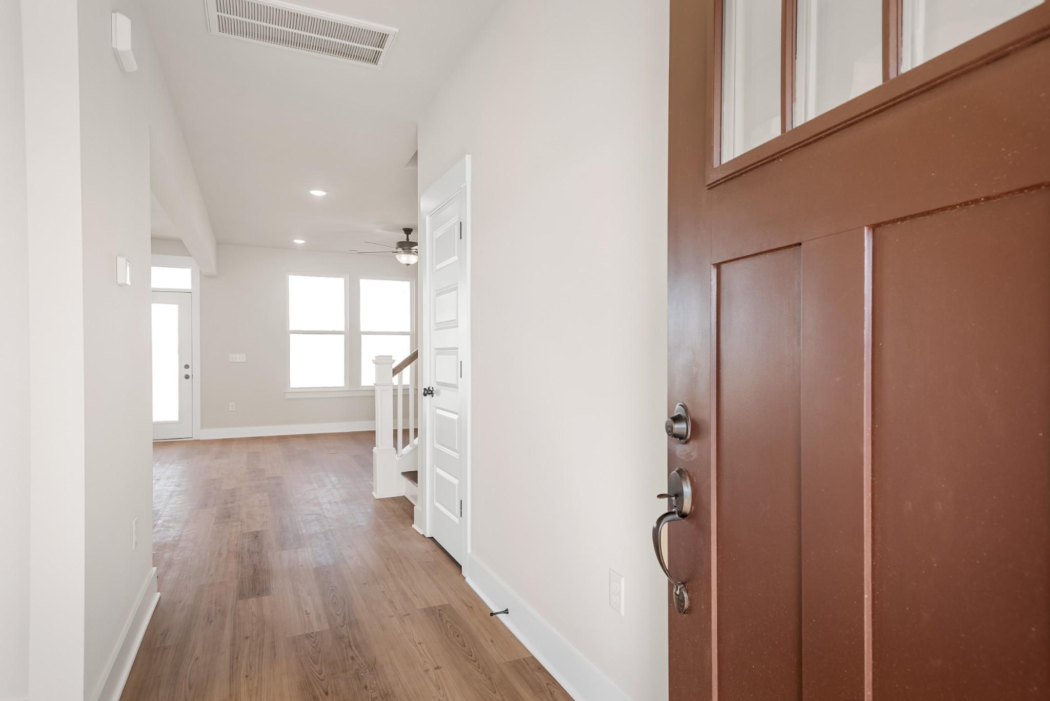 Welcoming entry foyer with hardwood floors, open staircase, and mahogany front door in Davidson Homes The Willow B, Calista Farms, White House, TN