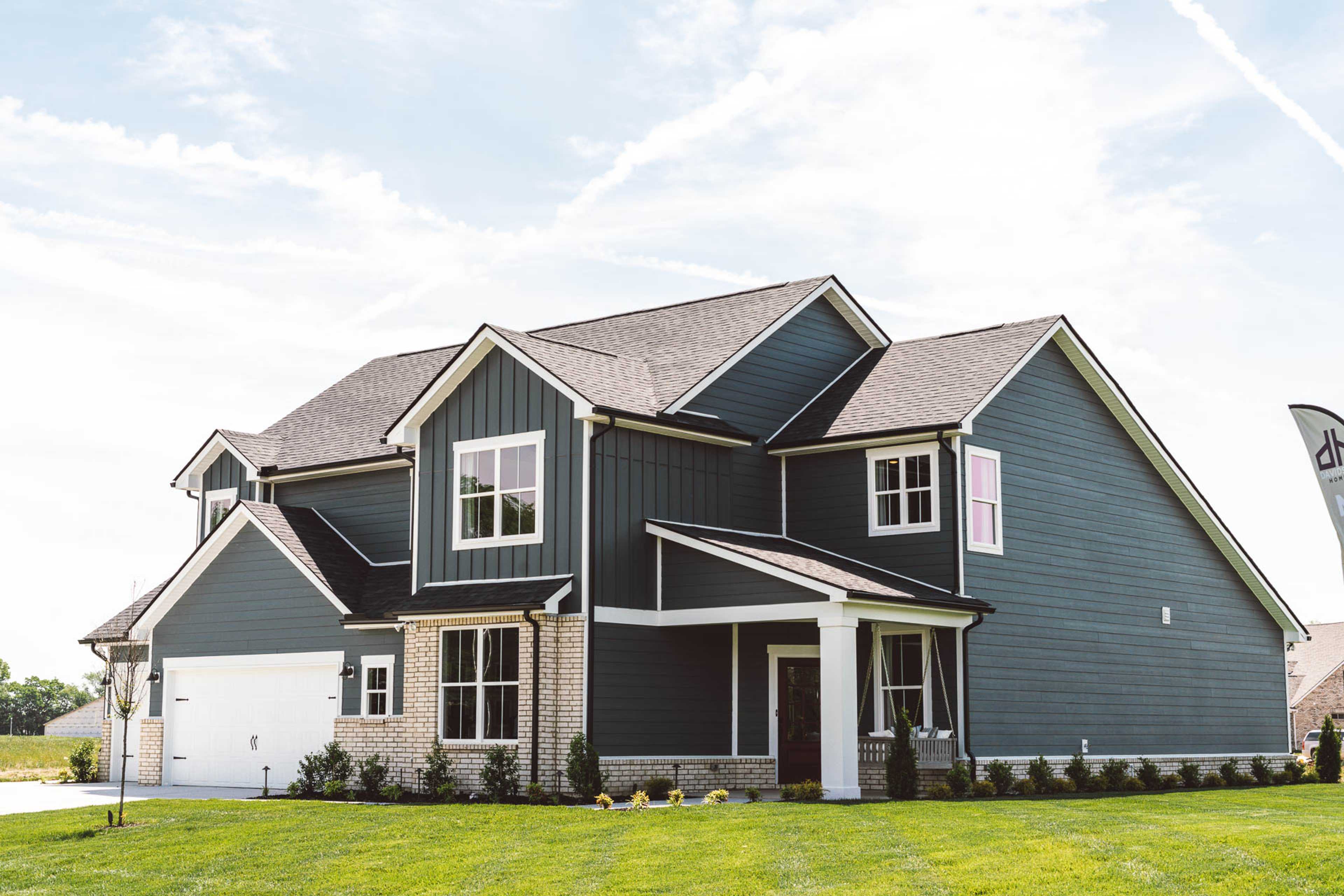 Navy two-story home exterior at Rivers Edge in Murfreesboro TN with brick accents, covered porch, and lush green lawn