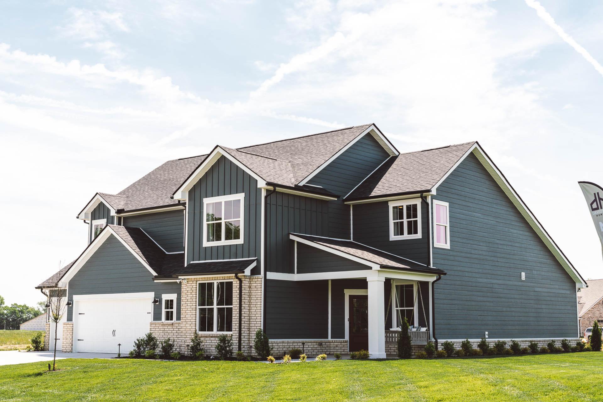Navy two-story home exterior at Rivers Edge in Murfreesboro TN with brick accents, covered porch, and lush green lawn