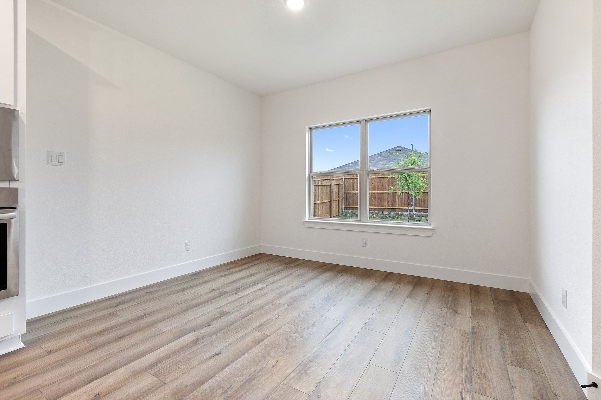 Bright bedroom with wood-look flooring and natural light in The Rockford C floor plan at Waverly Estates, Josephine, Texas.