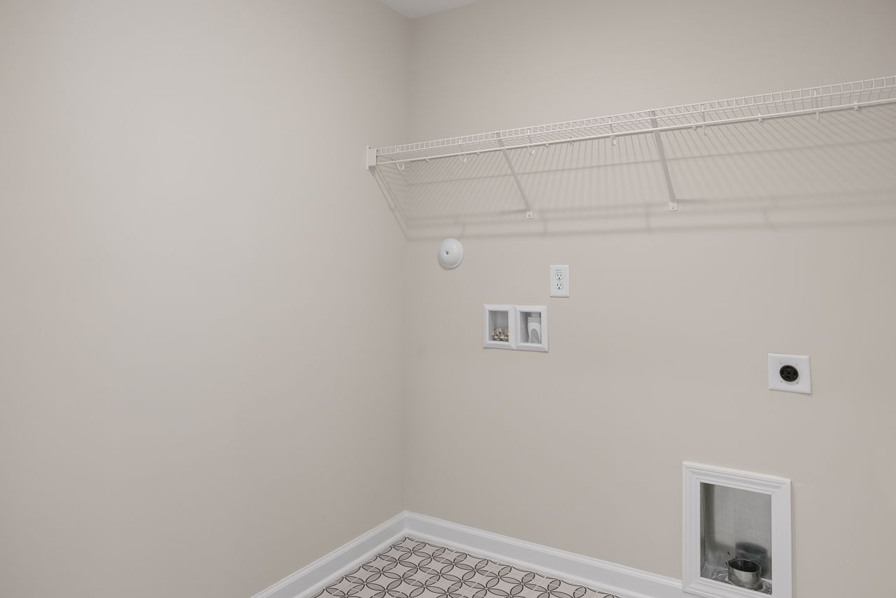 Laundry room area in The Chestnut by Davidson Homes featuring wire shelving and dedicated washer and dryer hookups.