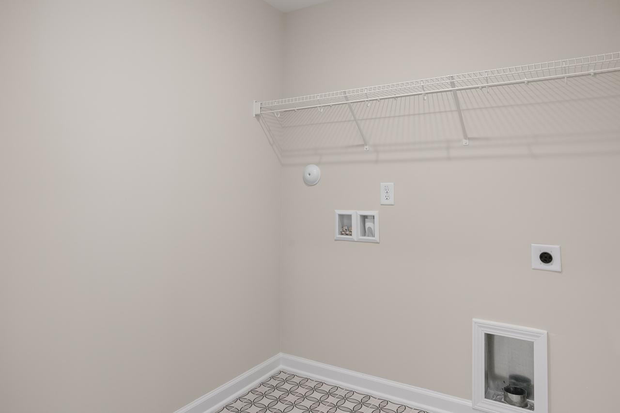 Laundry room area in The Chestnut by Davidson Homes featuring wire shelving and dedicated washer and dryer hookups.