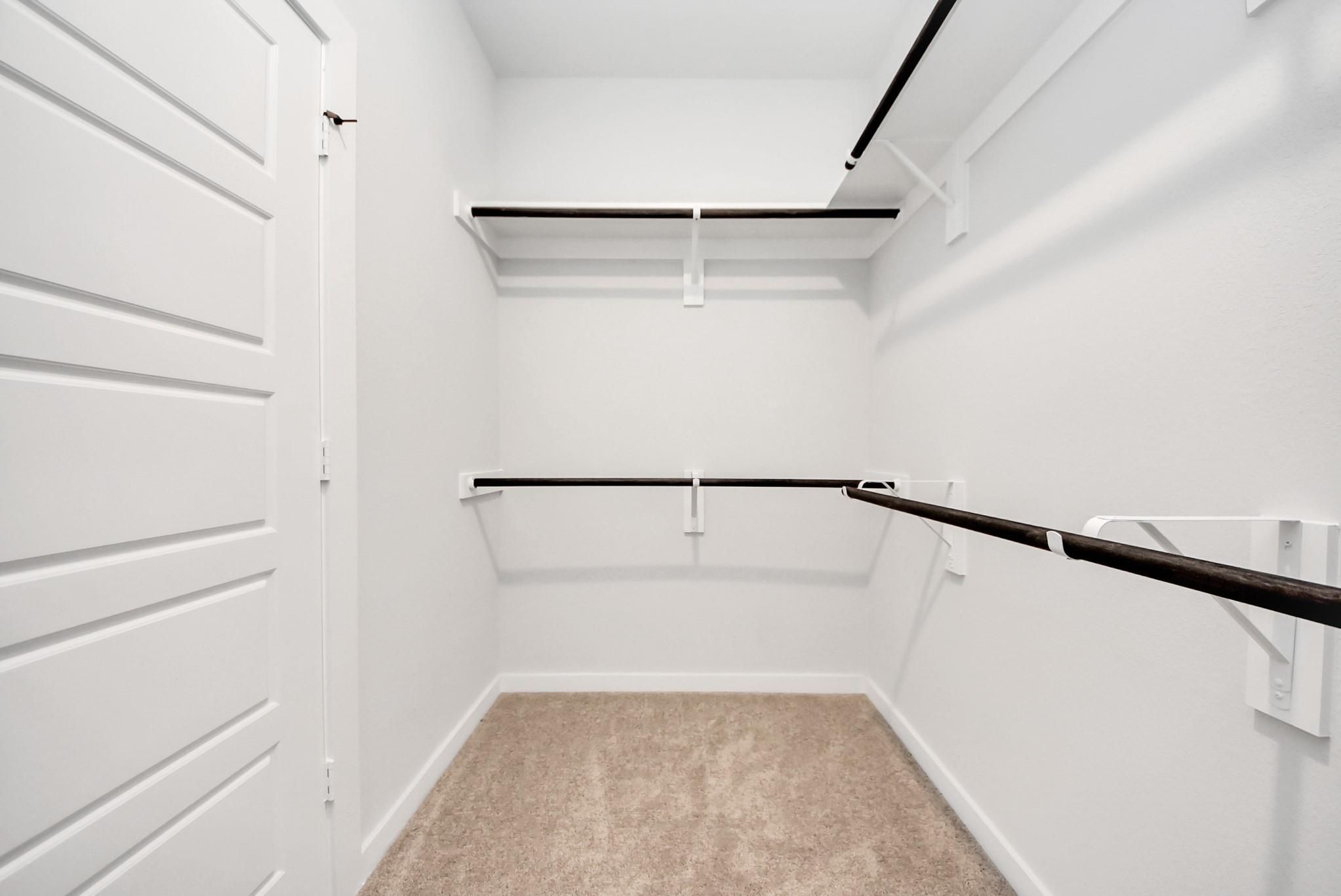 Spacious walk-in closet with shelving in The Daphne F floor plan at Sundance Cove in Crosby, Texas.