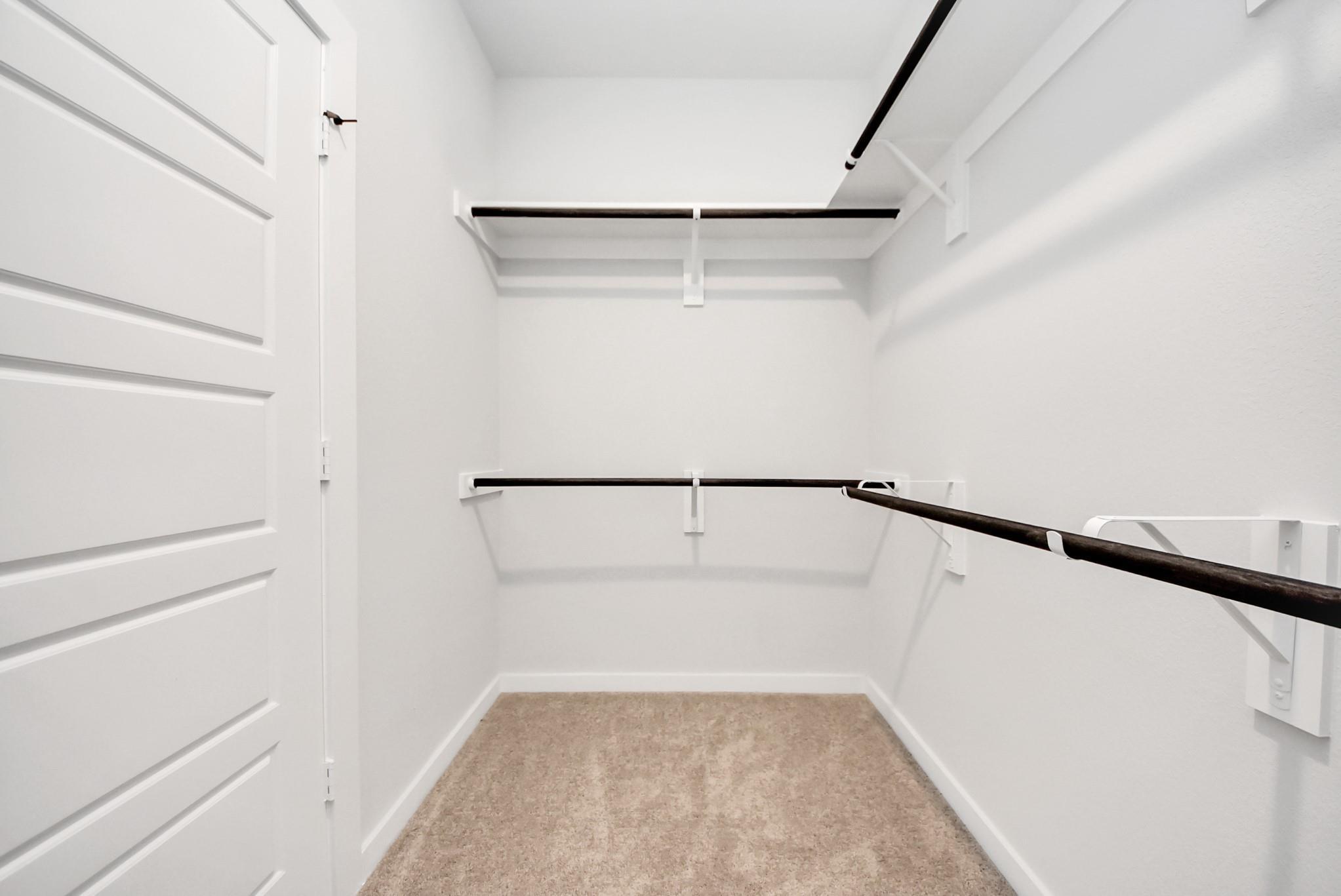 Spacious walk-in closet with shelving in The Daphne F floor plan at Sundance Cove in Crosby, Texas.