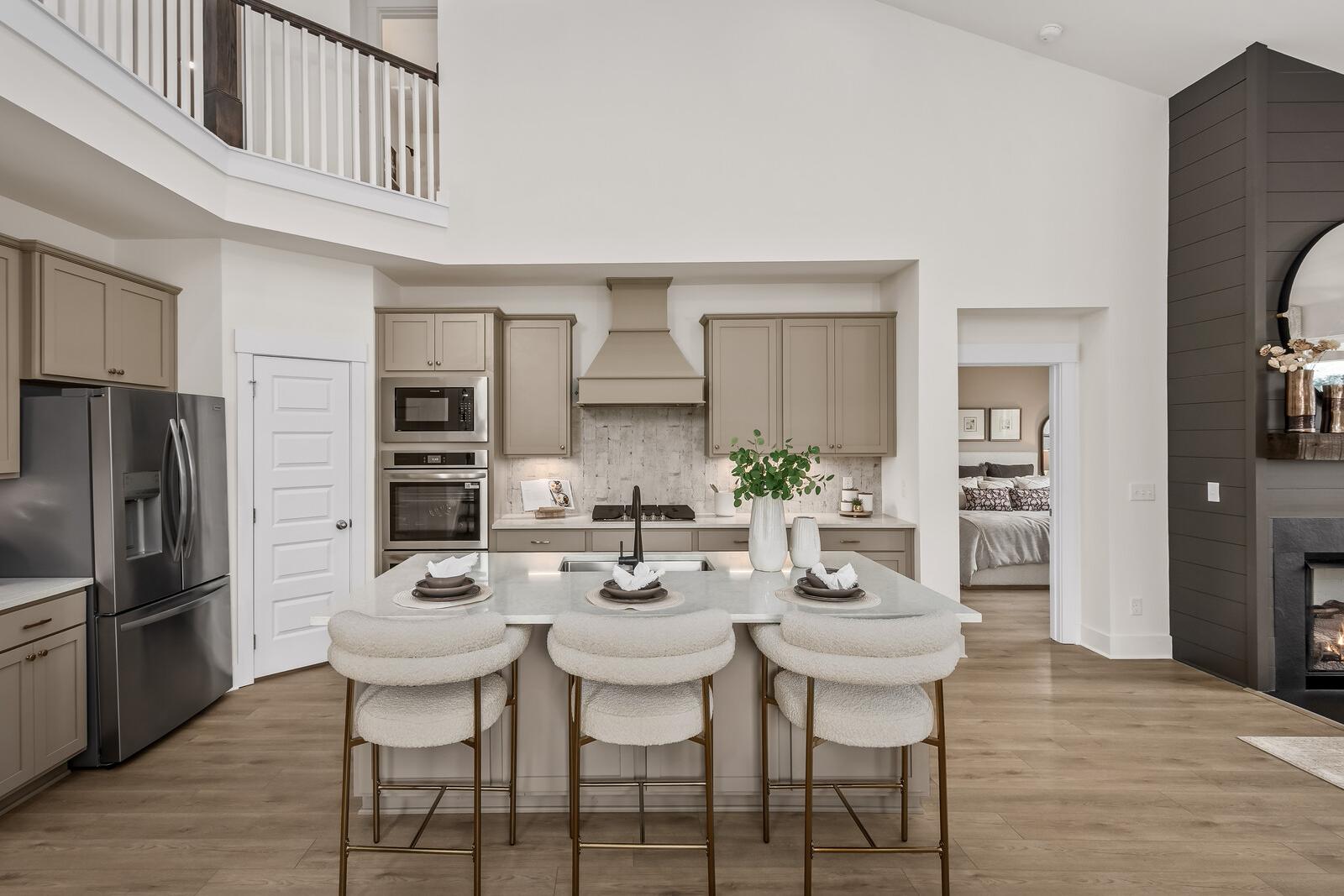 Spacious open-concept kitchen at Benders Cove in Mt. Juliet TN with beige cabinets, island bar seating, stainless appliances, and loft overlook