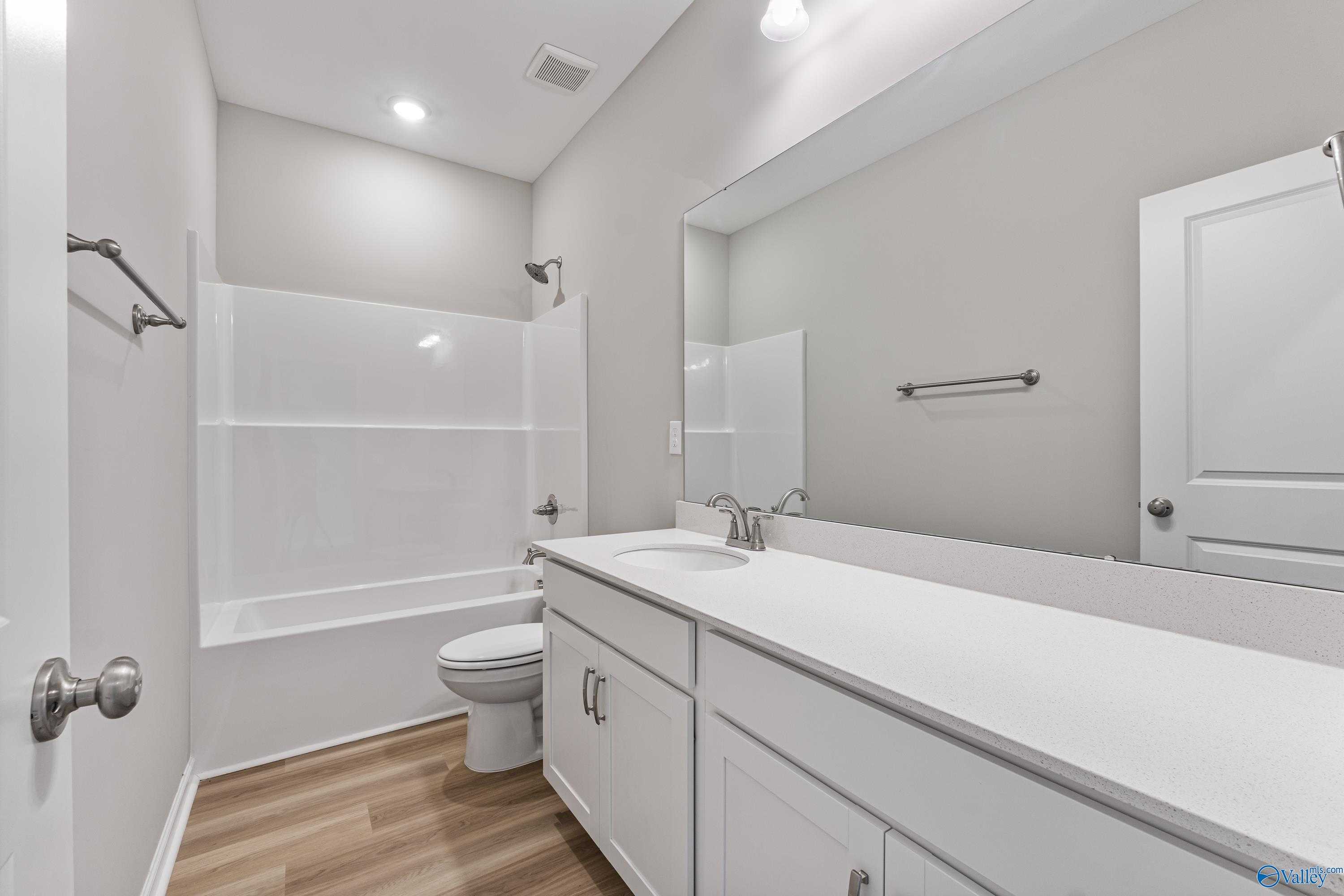 Bright secondary bathroom featuring white tub-shower combo, vanity sink, and toilet in Davidson Homes The Phoenix, Hazel Green, AL