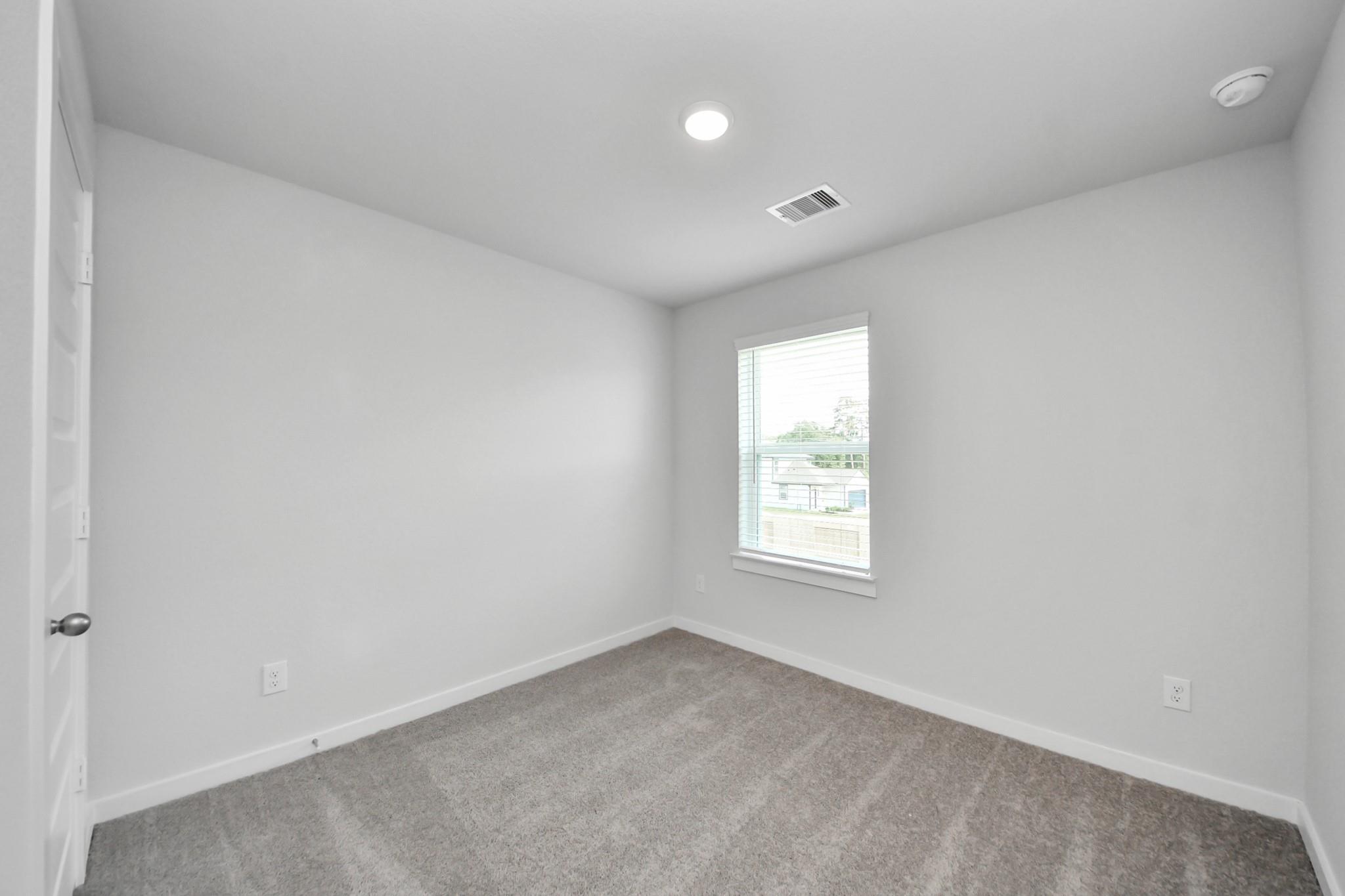 Neutral bedroom with carpet and window in The Brazos F floor plan at Liberty Estates, Cleveland, Texas by Davidson Homes.