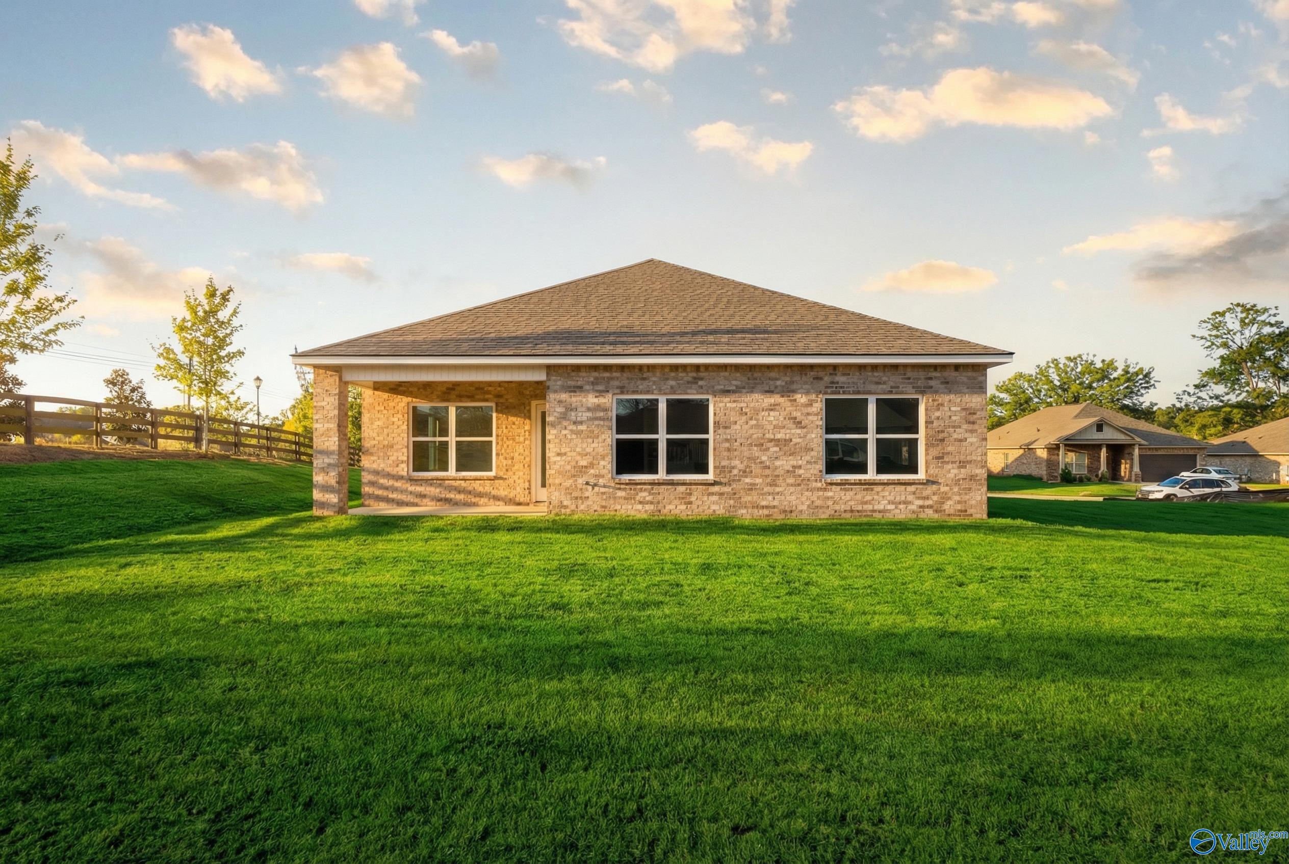 Single-story brick home with gabled roof, covered entry, and lush green lawn in Flint Meadows, New Market, Alabama