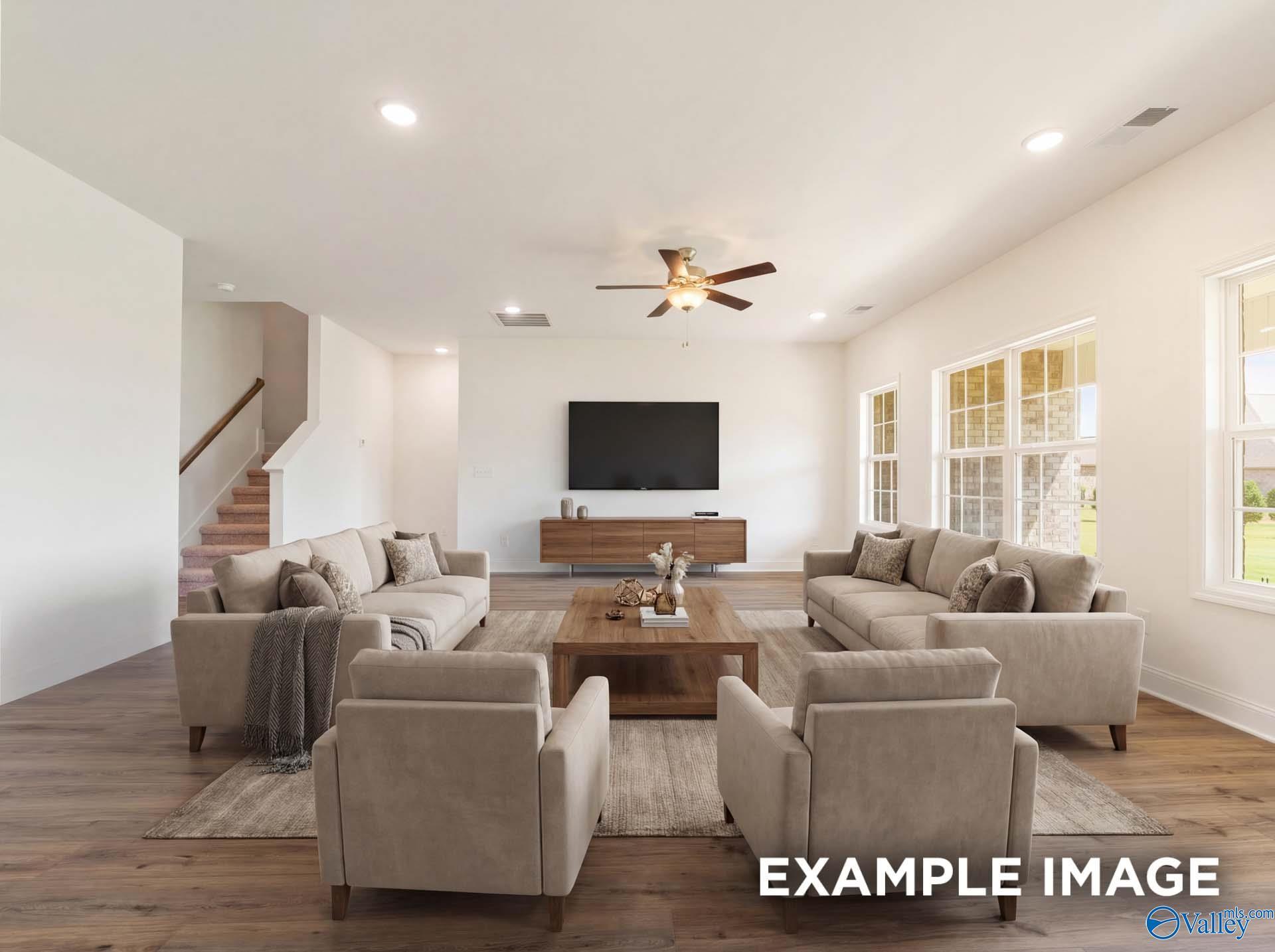 Spacious open-concept living room with neutral sofas in The Rockford B floor plan at Kendall Downs, Toney, Alabama.