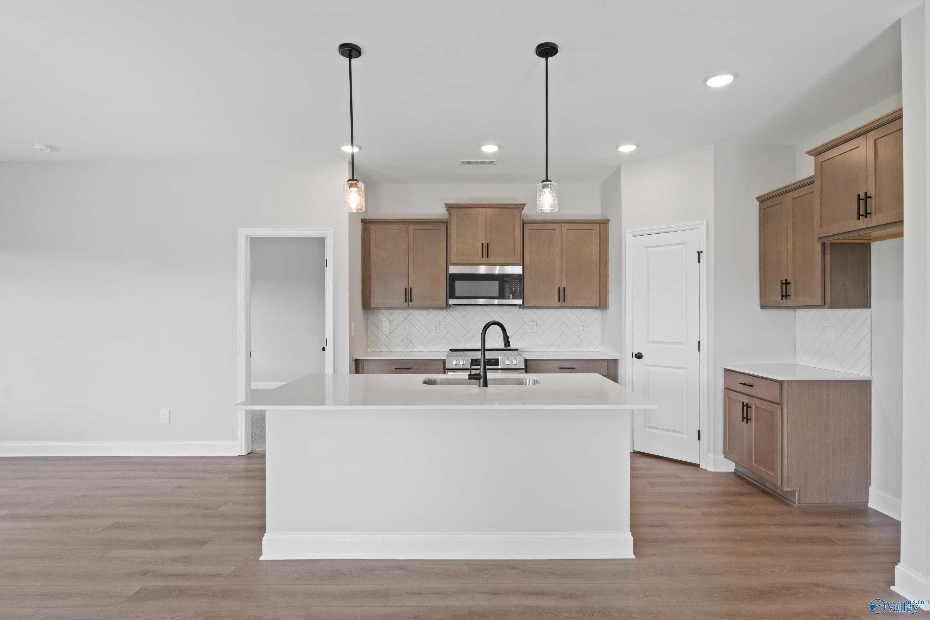 Modern kitchen featuring white quartz island, stainless appliances, and pendant lights in Davidson Homes The Franklin C, Hazel Green, Alabama