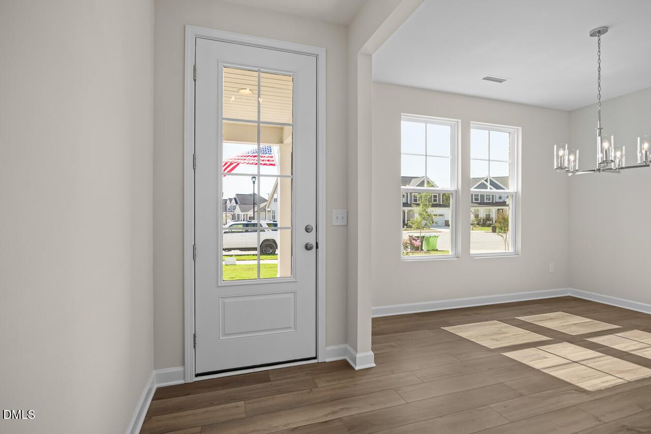 Bright entryway with glass-paneled front door and hardwood floors in Davidson Homes The Willow C, Woodland Crossing, Zebulon NC