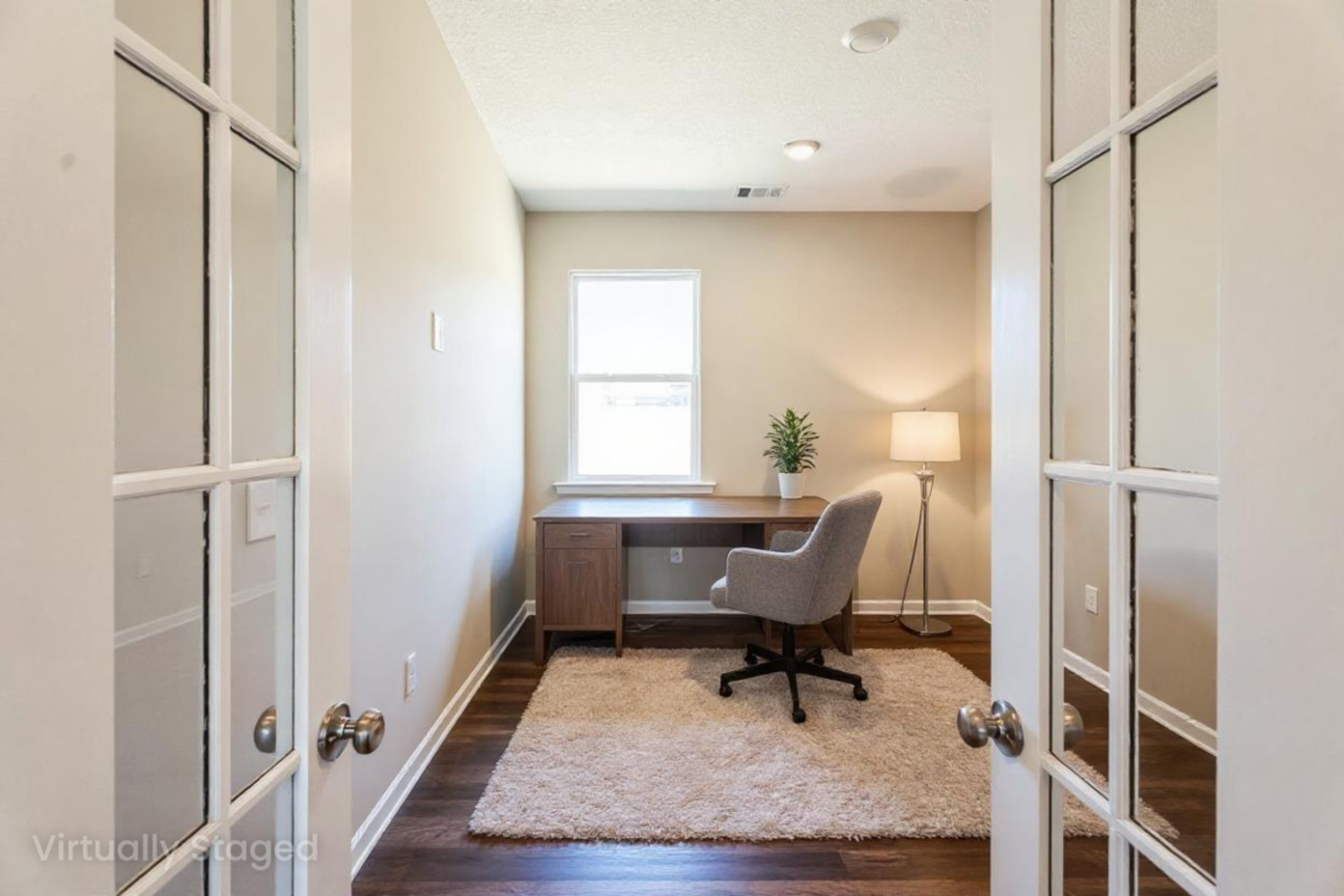 Spacious home office in Heatherbrook Phenix City Alabama by Evermore Homes with desk chair window plant rug and French doors