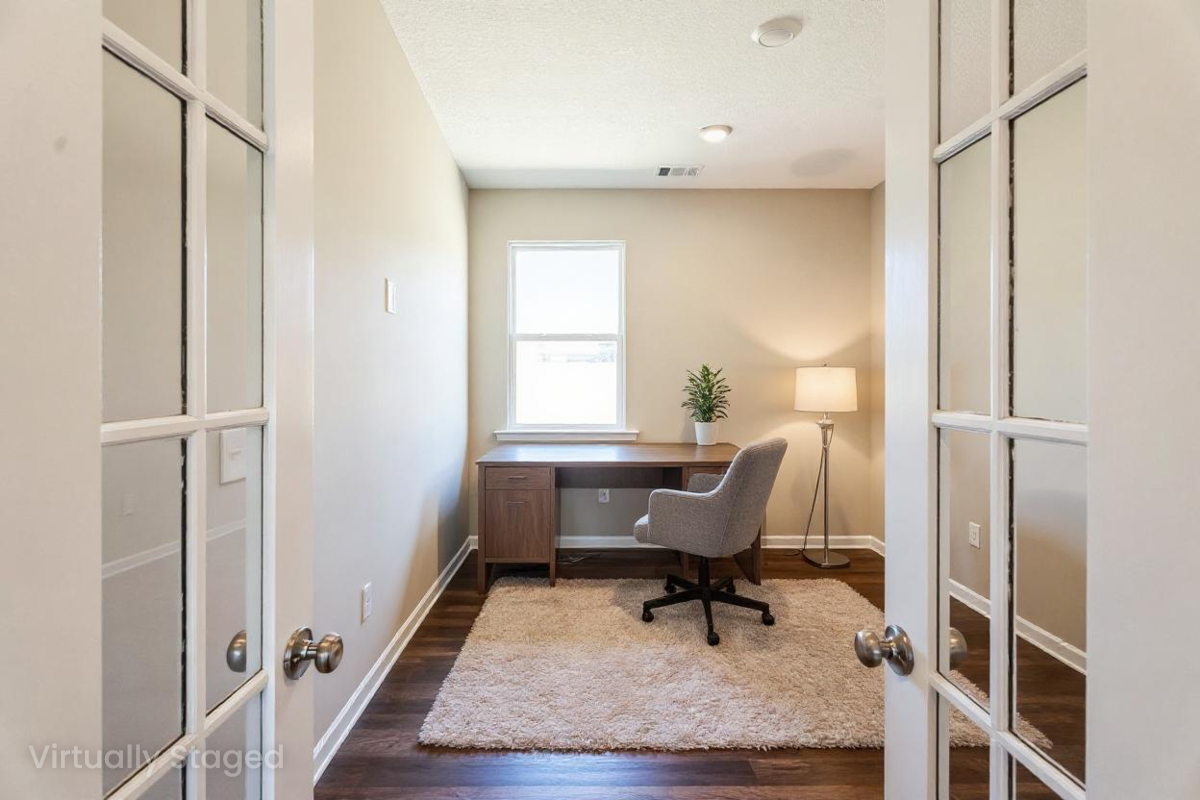 Spacious home office in Heatherbrook Phenix City Alabama by Evermore Homes with desk chair window plant rug and French doors