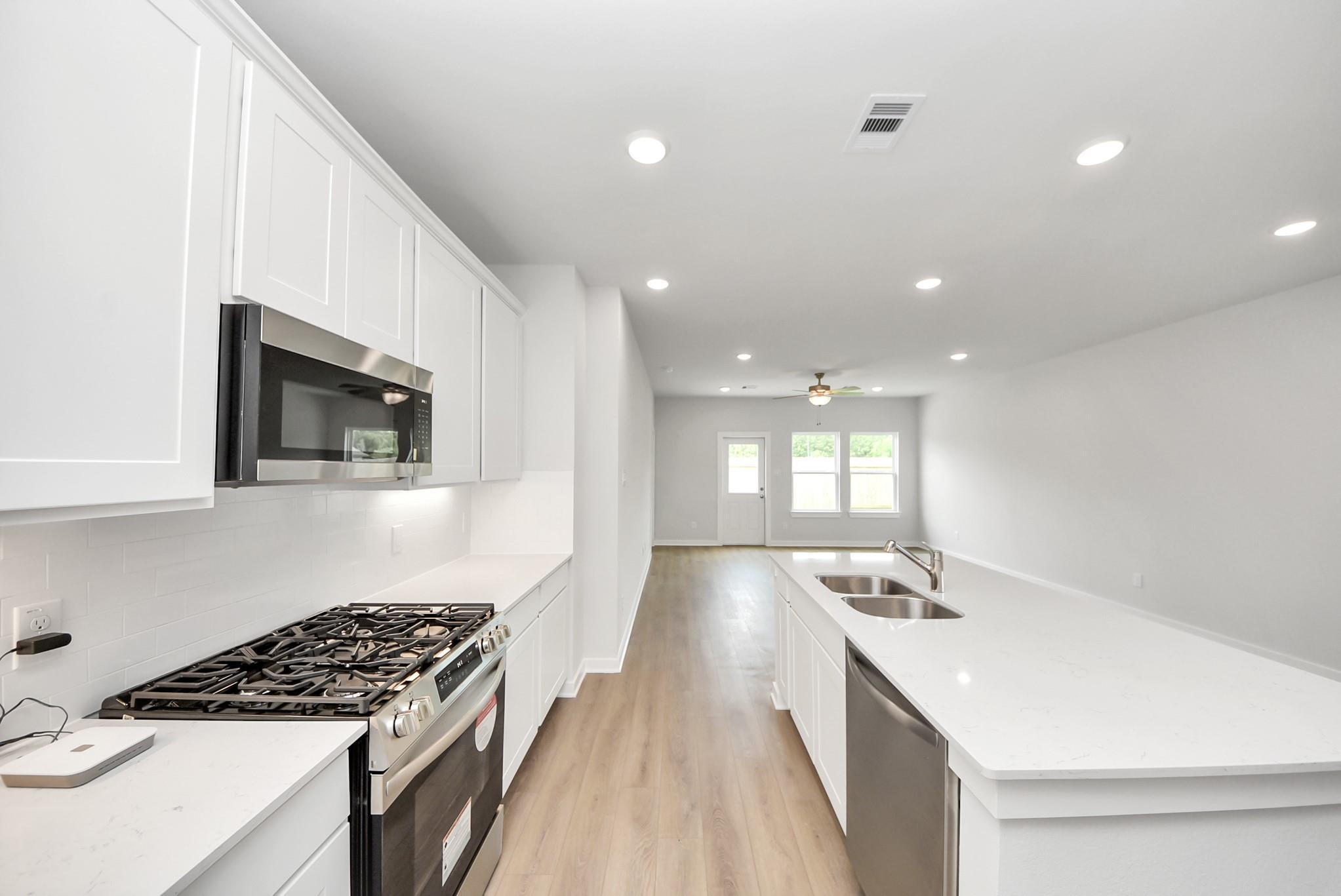Modern kitchen with white cabinets, quartz countertops, and stainless appliances in The Blanco E at The Villages, Dayton.