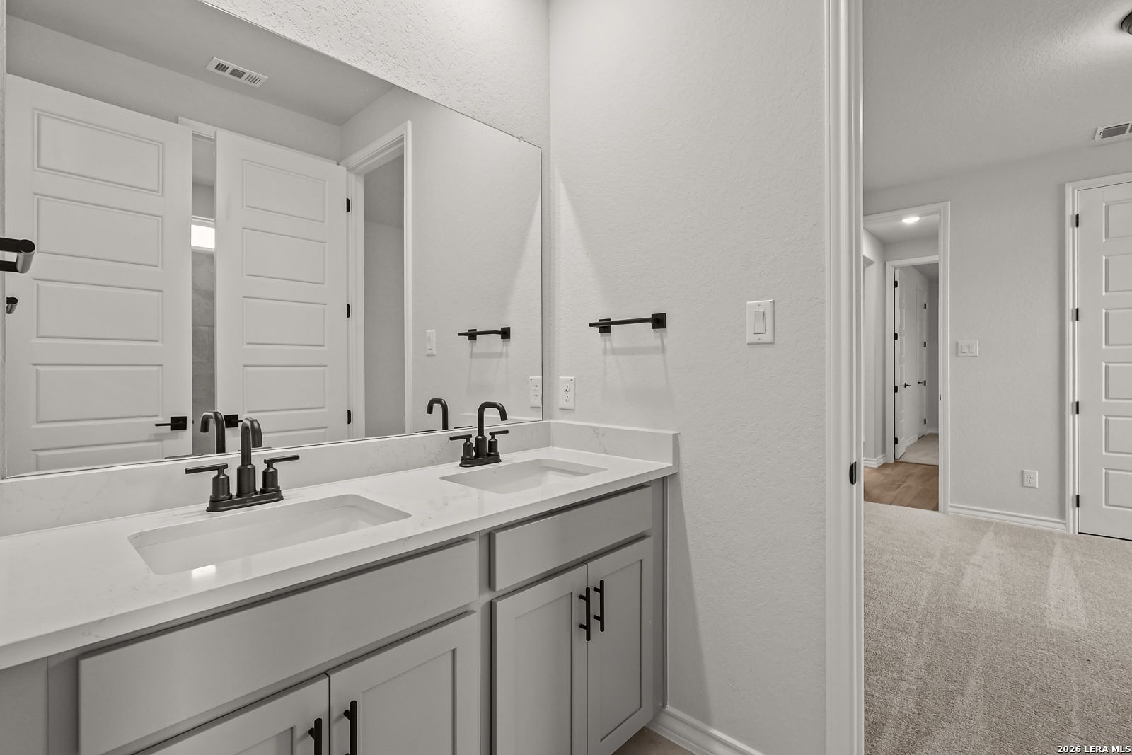 Double vanity bathroom with quartz countertops and black fixtures in Davidson Homes The Oxford F, Potranco Oaks, Castroville TX