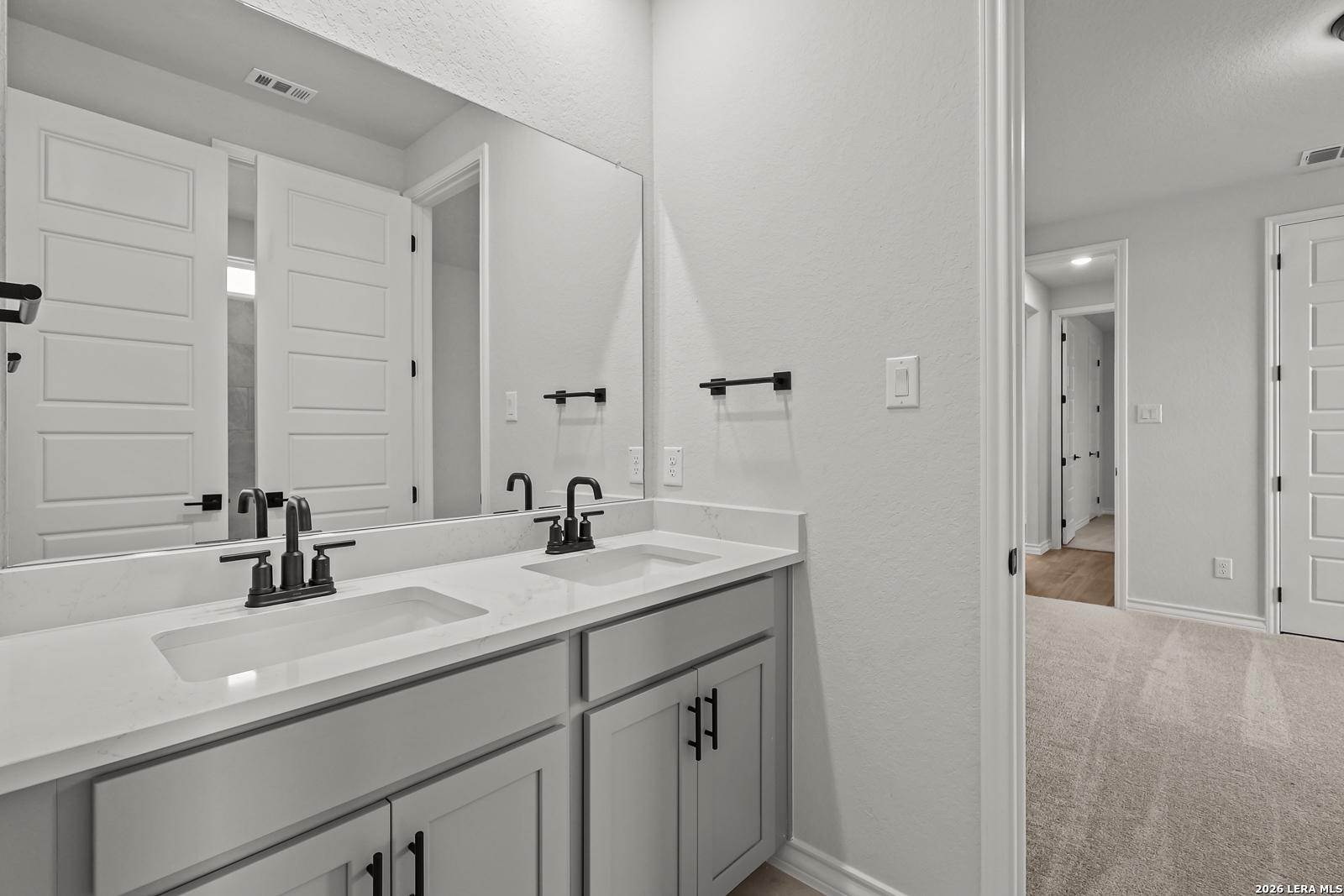Double vanity bathroom with quartz countertops and black fixtures in Davidson Homes The Oxford F, Potranco Oaks, Castroville TX