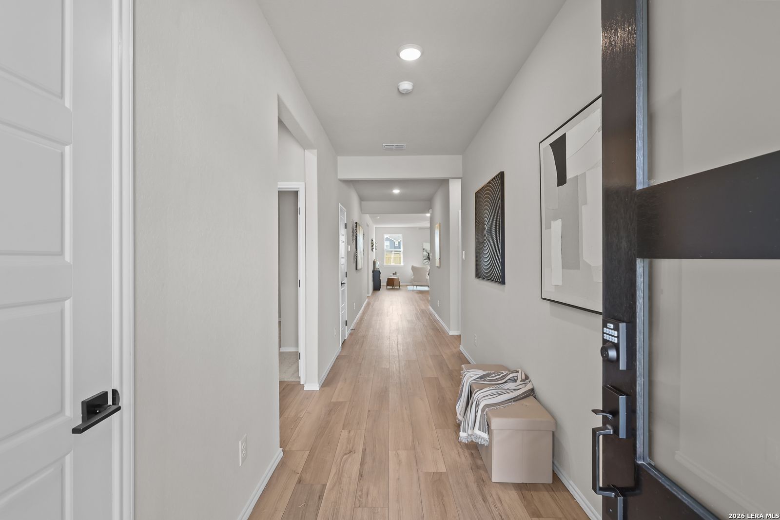 Bright entry hallway with wood-look flooring and modern black front door in Davidson Homes Daphne H plan, Seguin, Texas