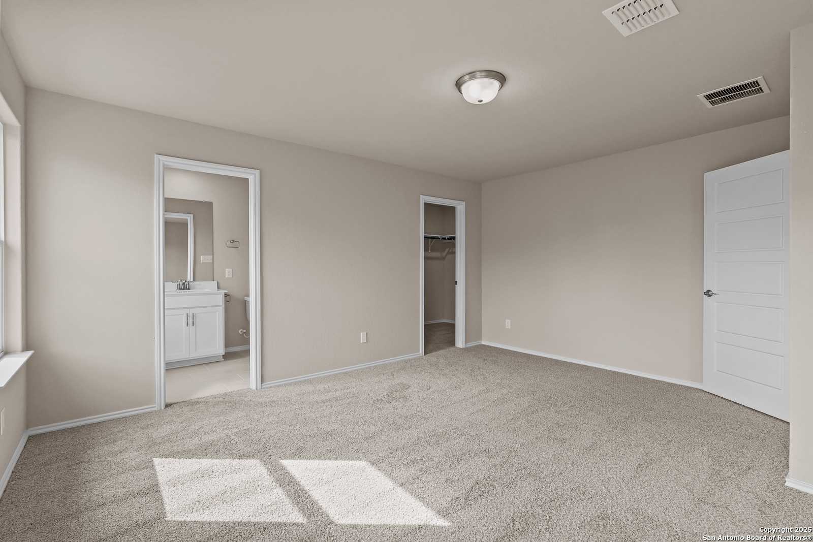 Spacious master bedroom suite with en-suite bath vanity and walk-in closet in Davidson Homes The Douglas G, San Antonio, Texas