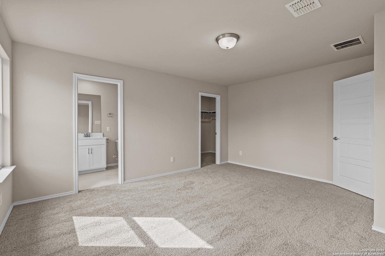 Spacious master bedroom suite with en-suite bath vanity and walk-in closet in Davidson Homes The Douglas G, San Antonio, Texas