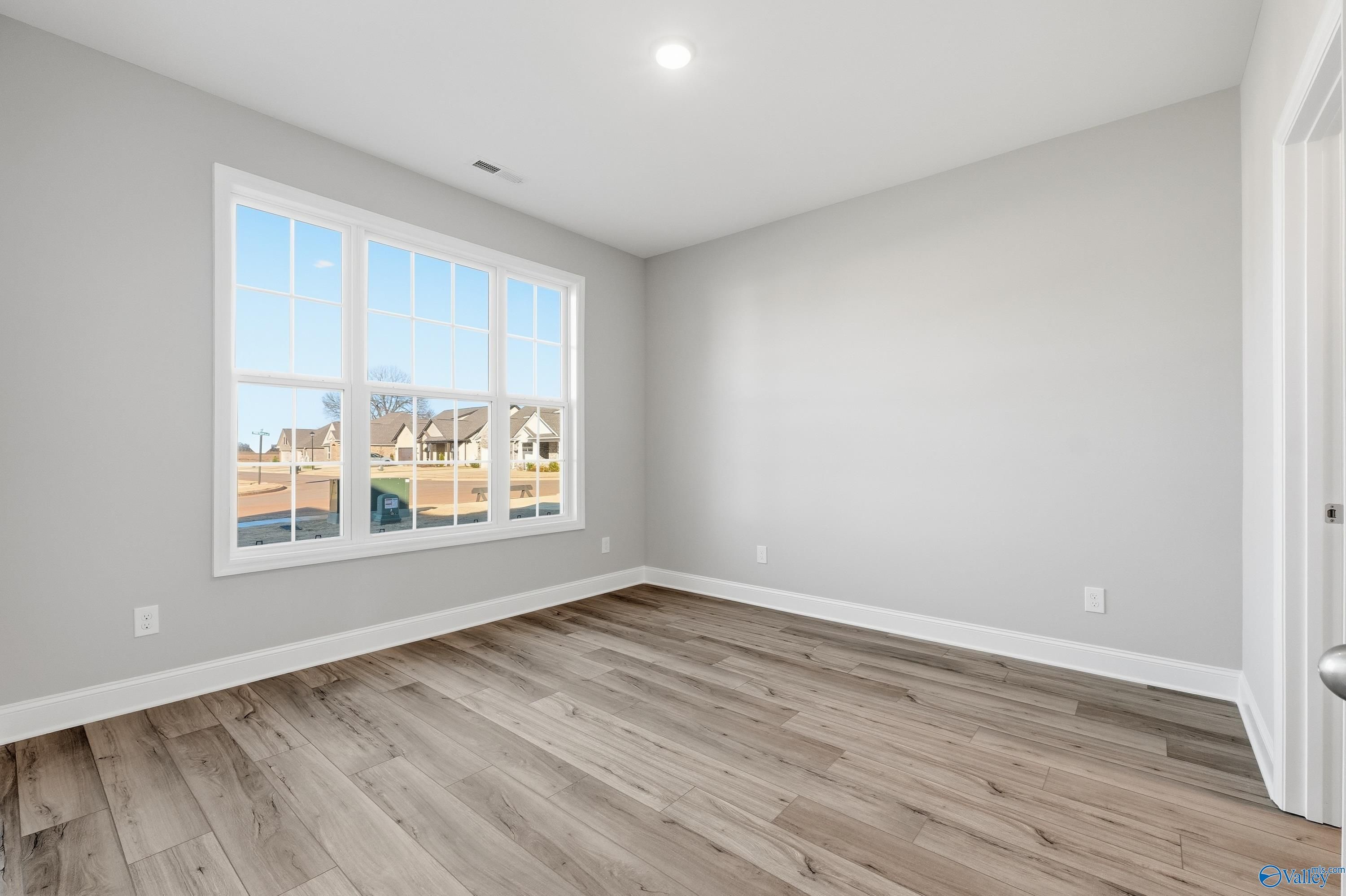 Bright secondary bedroom with large window overlooking neighborhood in The Lanier floor plan, Toney, Alabama