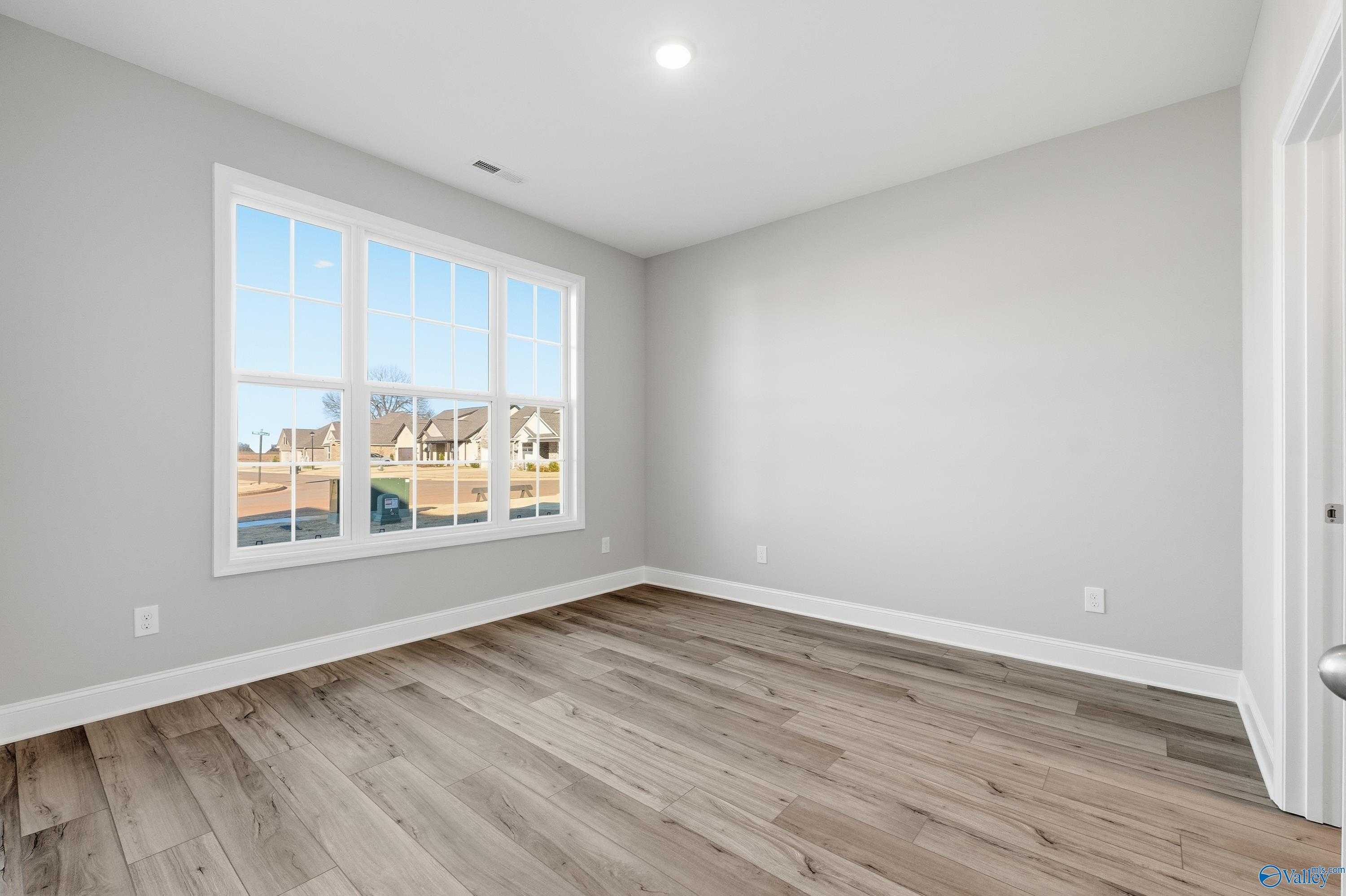 Bright secondary bedroom with large window overlooking neighborhood in The Lanier floor plan, Toney, Alabama