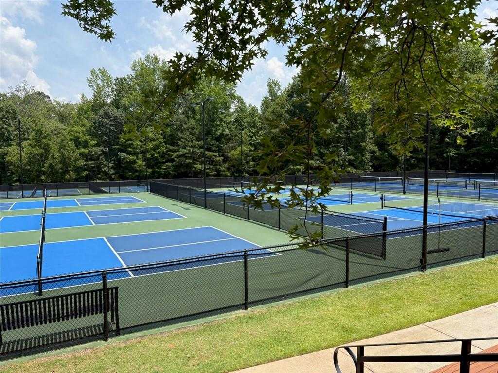 Vibrant blue tennis courts surrounded by fences and oak trees in Riverwood, Dallas, Georgia community