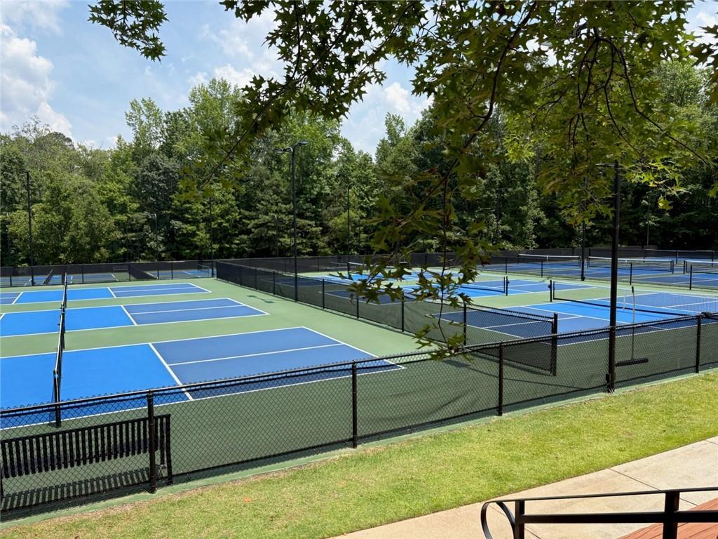 Vibrant blue tennis courts surrounded by fences and oak trees in Riverwood, Dallas, Georgia community