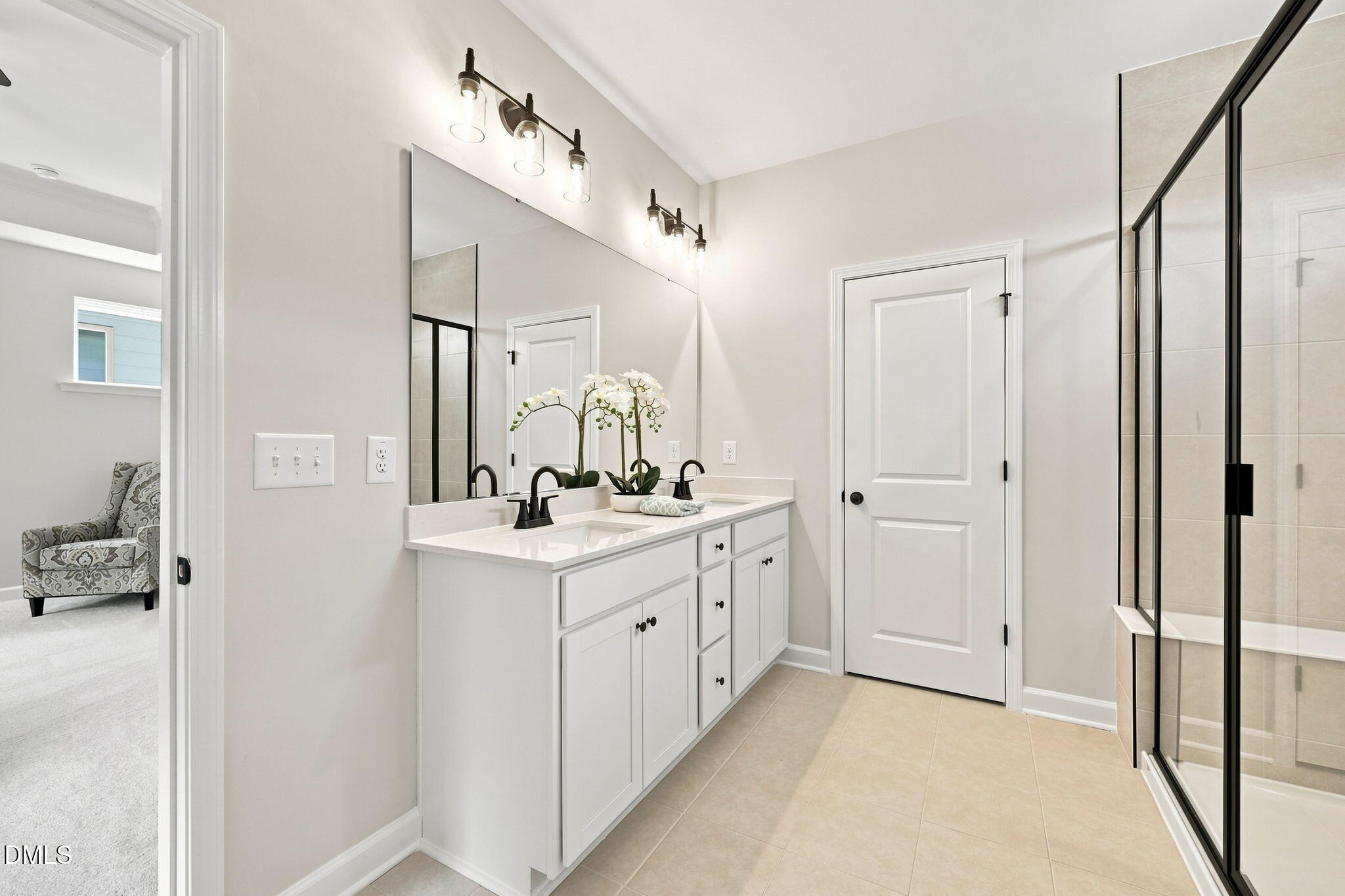 Modern primary bathroom with double vanity and glass-enclosed shower in The Harris C home at Forestville Yard, Knightdale.
