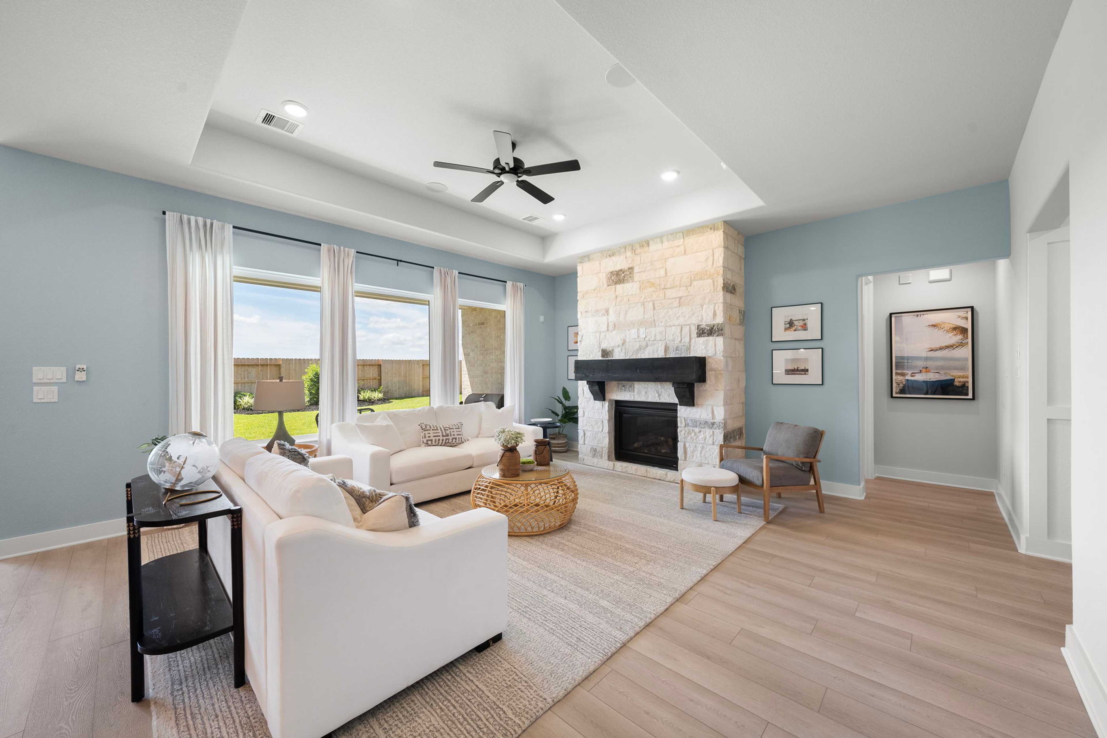 Spacious open-concept living room in Lago Mar with stone fireplace, white sofas, large windows, hardwood floors, Texas City TX