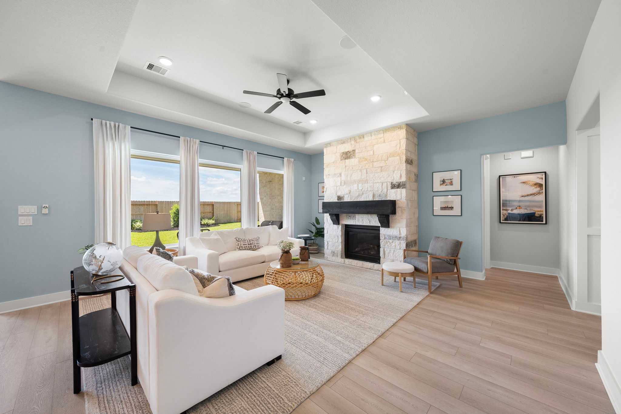 Spacious open-concept living room in Lago Mar with stone fireplace, white sofas, large windows, hardwood floors, Texas City TX
