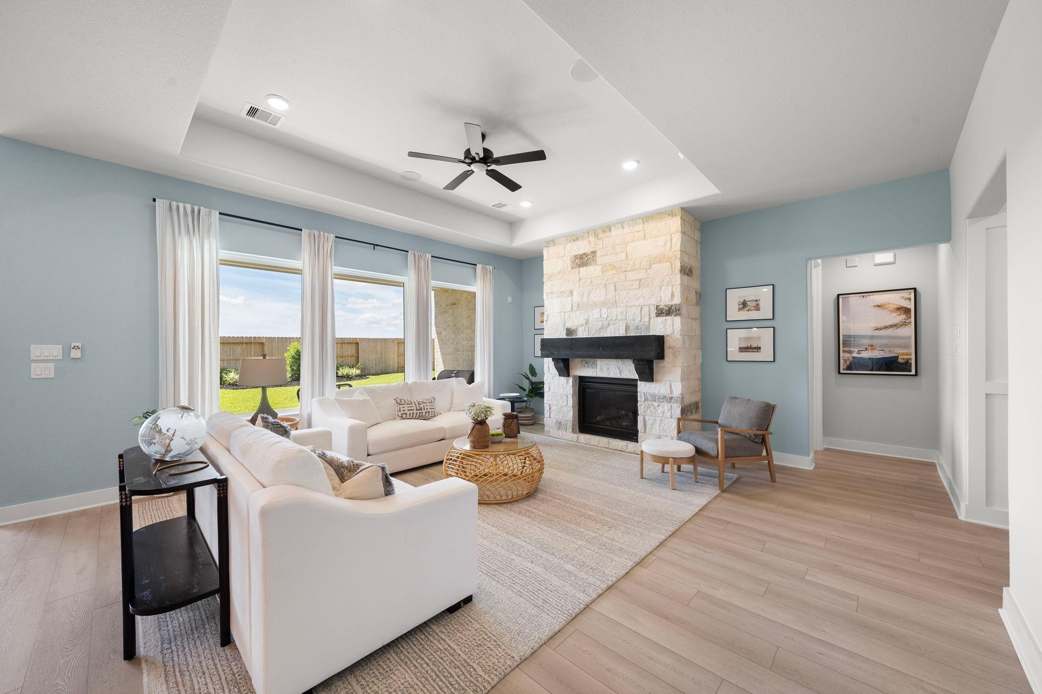 Spacious open-concept living room in Lago Mar with stone fireplace, white sofas, large windows, hardwood floors, Texas City TX