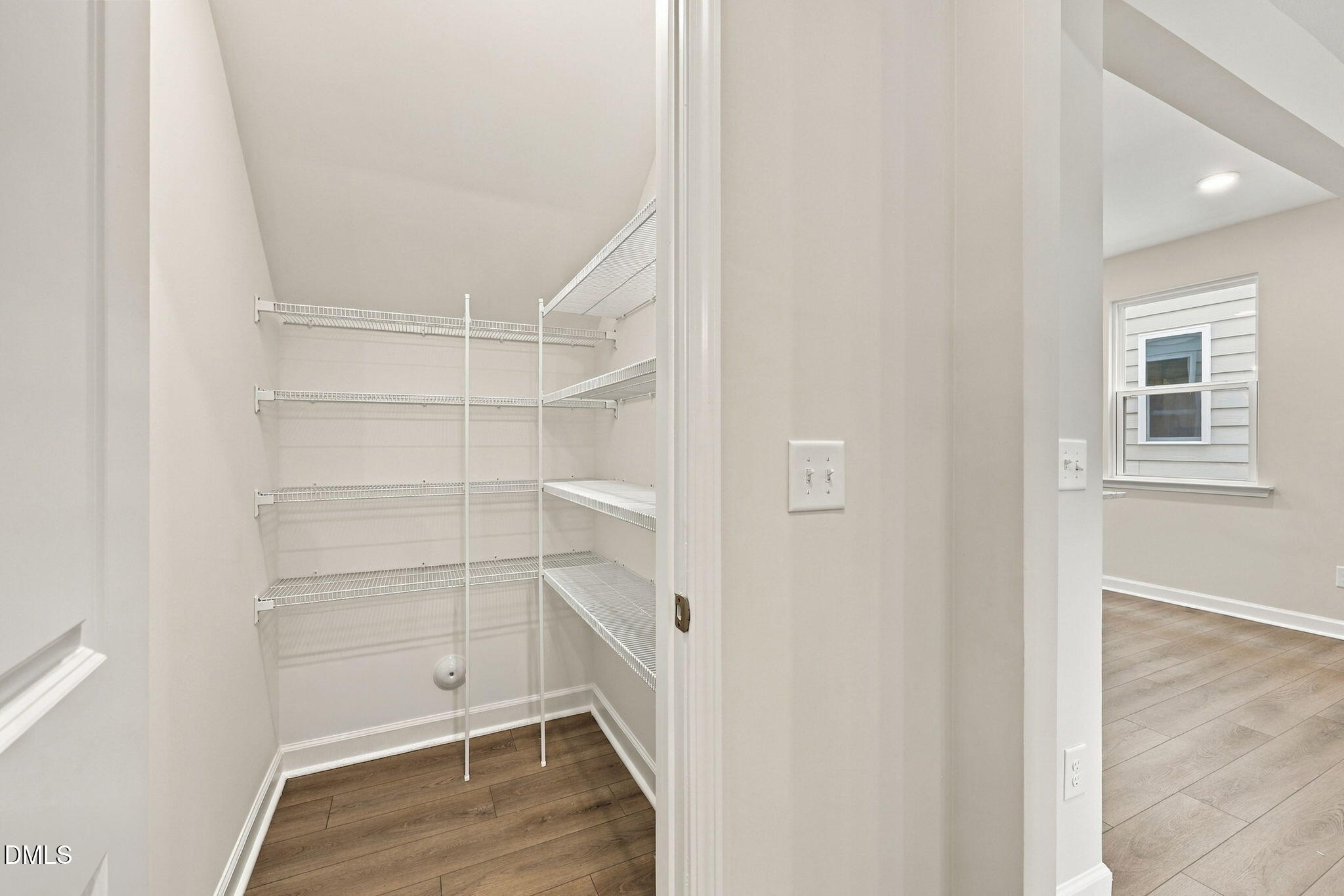 Walk-in closet with white wire shelving and wood-look flooring in Davidson Homes The Alexander B, Knightdale, NC
