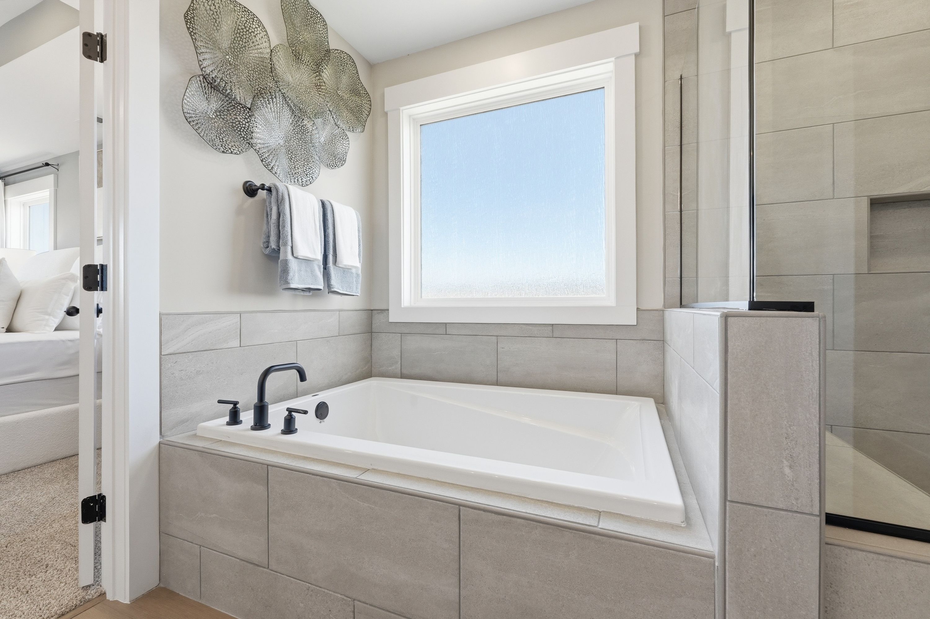 Elegant master bathroom at Berry Cove in New Market Alabama with corner soaking tub, subway tiles, and large window