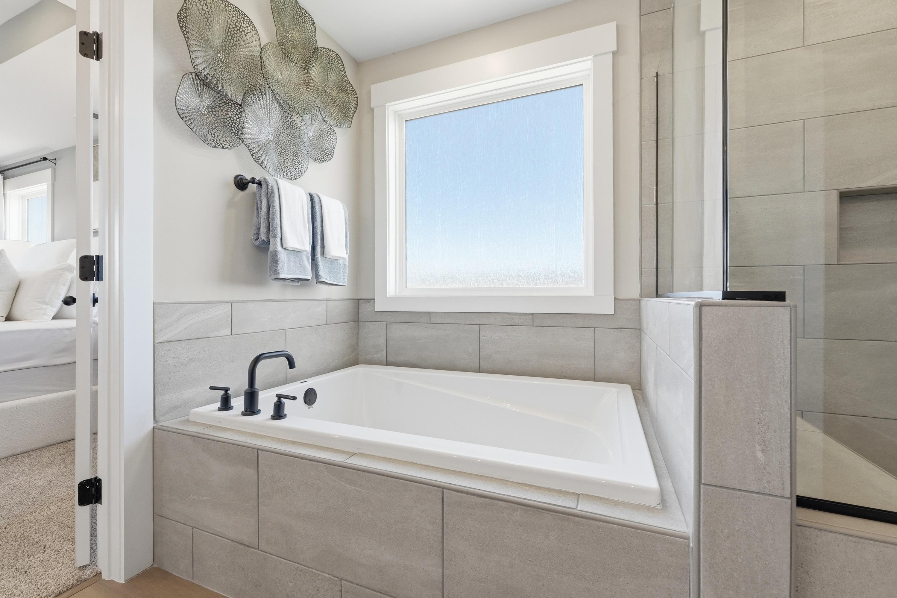 Elegant master bathroom at Berry Cove in New Market Alabama with corner soaking tub, subway tiles, and large window