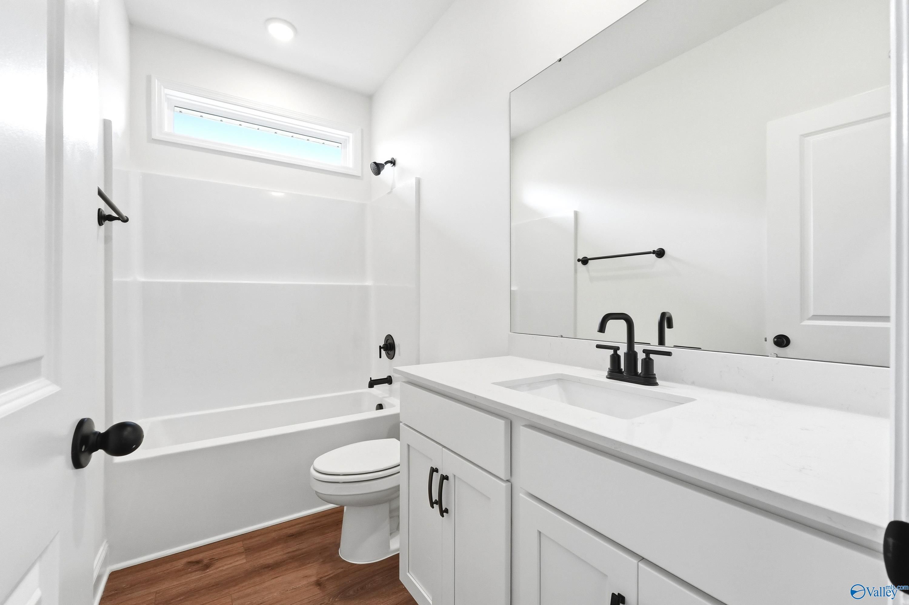 Modern bathroom with white vanity, matte black fixtures, and tub-shower combo in The Daphne C home, Ivy Hills, Toney, AL.