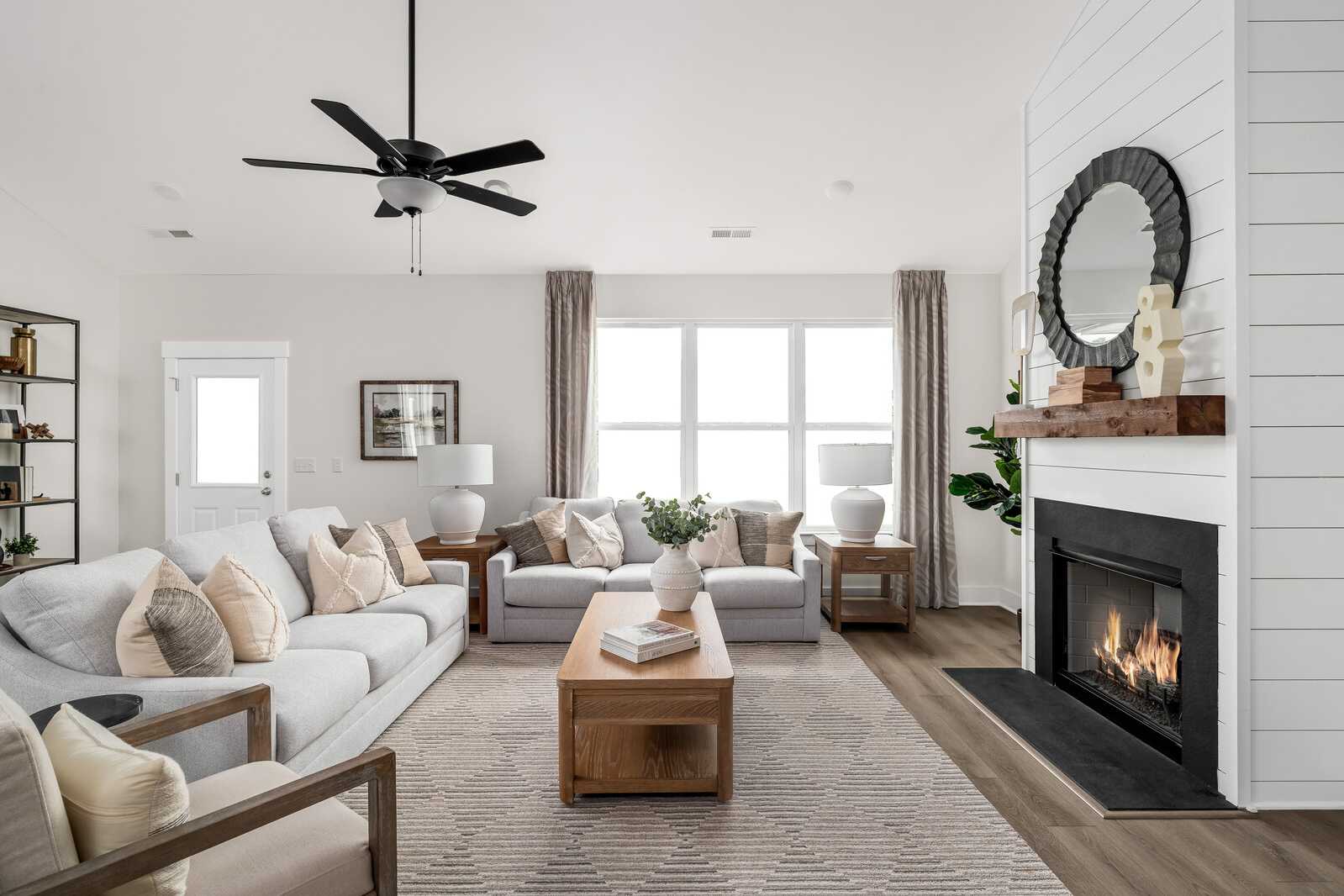 Spacious living room in Woods Crossing, Gallatin TN with shiplap walls, gas fireplace, beige sofa, and ceiling fan