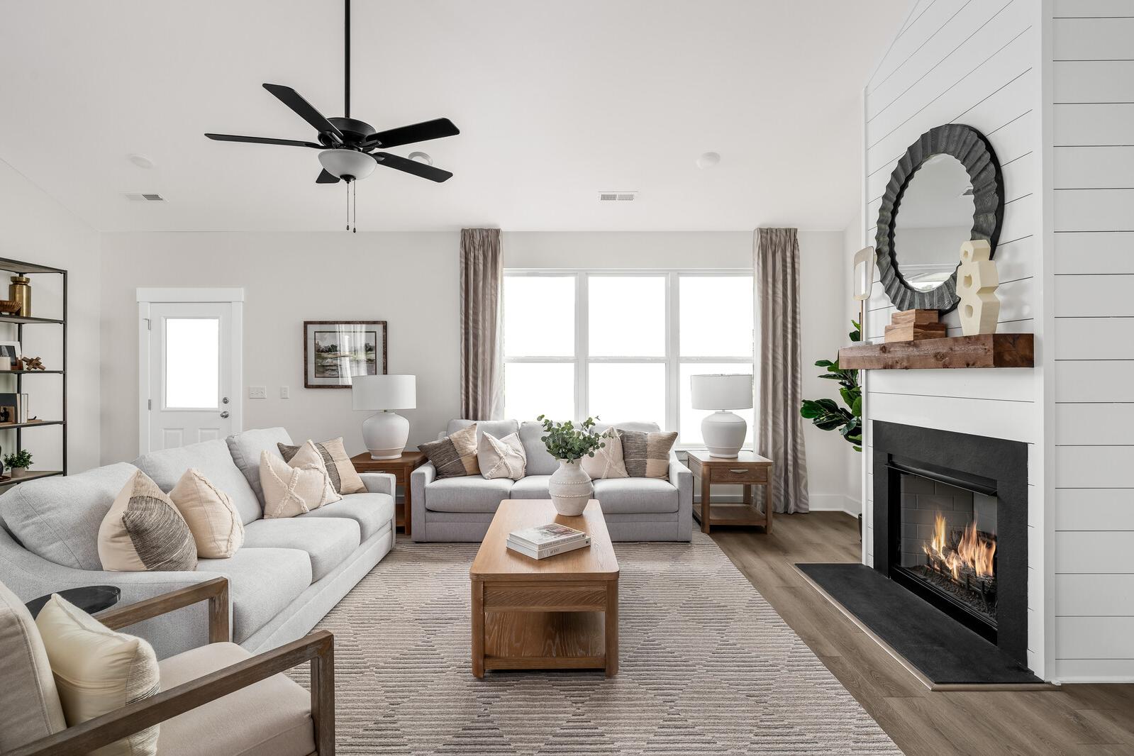 Spacious living room in Woods Crossing, Gallatin TN with shiplap walls, gas fireplace, beige sofa, and ceiling fan