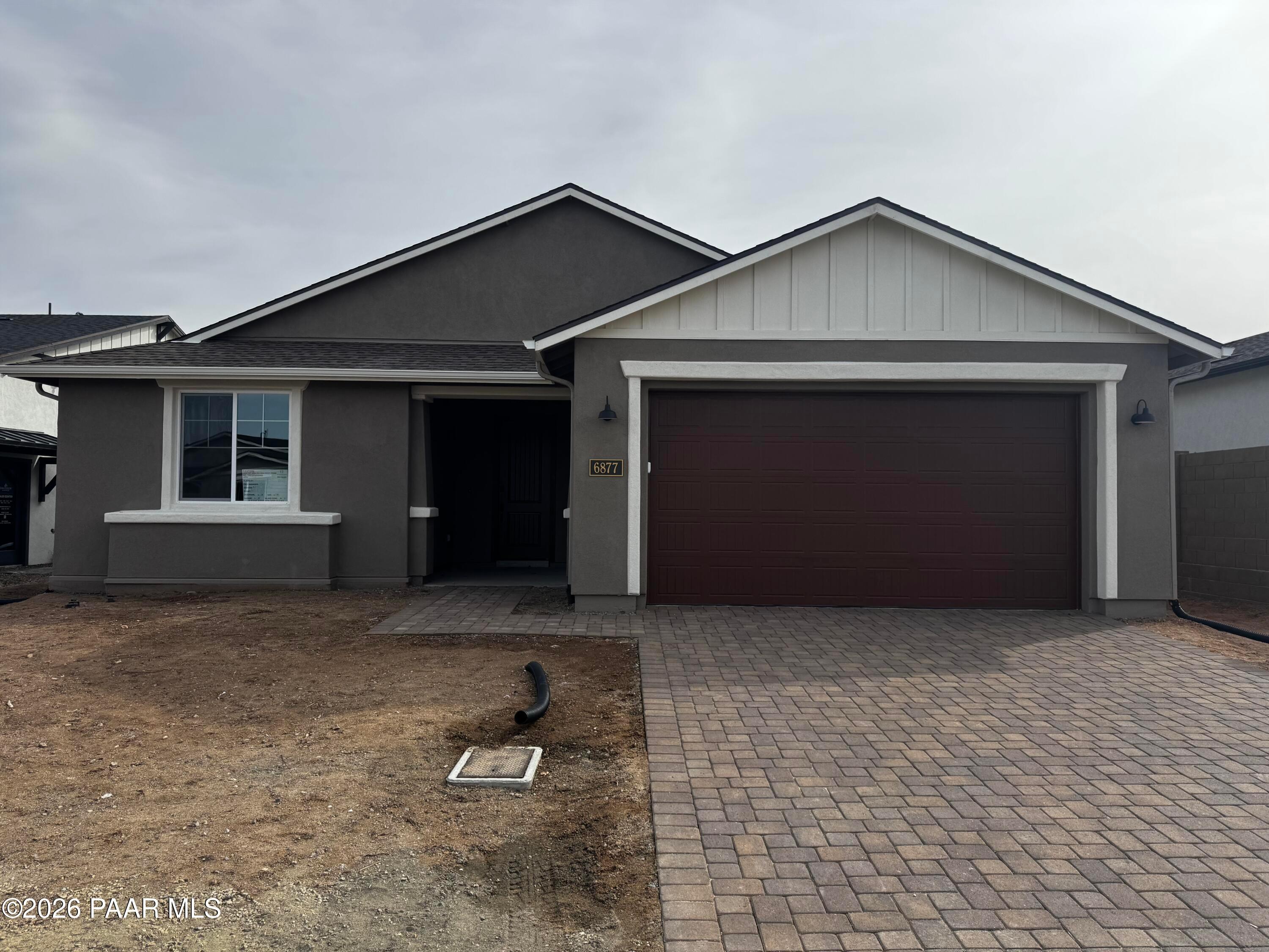 Modern 1-story Durango II B home by Davidson Homes in Westwood, Prescott, AZ: gray exterior, maroon 3-car garage, paver driveway