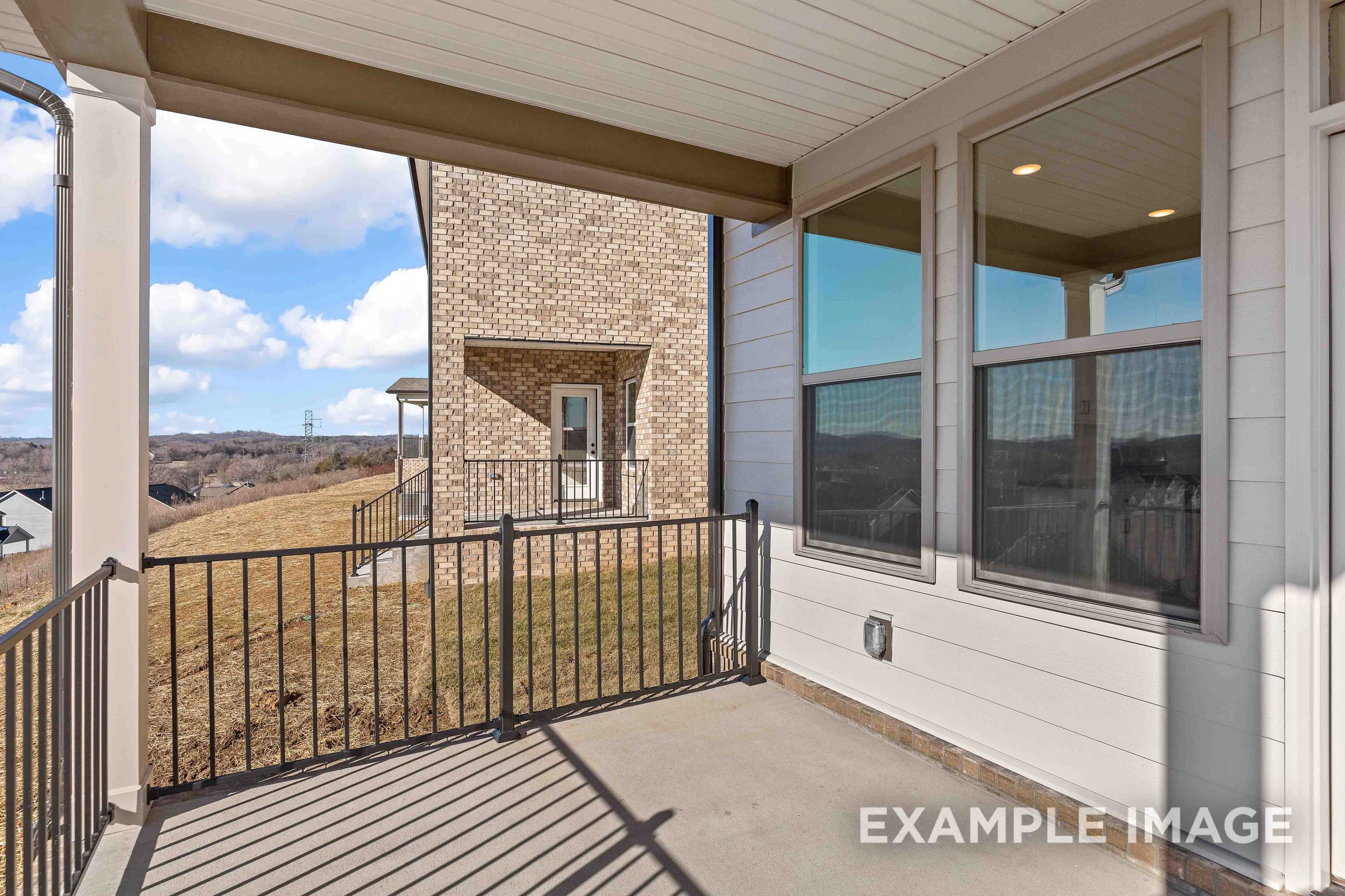 Covered patio of The Willow C 2-story home featuring large windows, white siding, brick accents, and black railing in Mt. Juliet