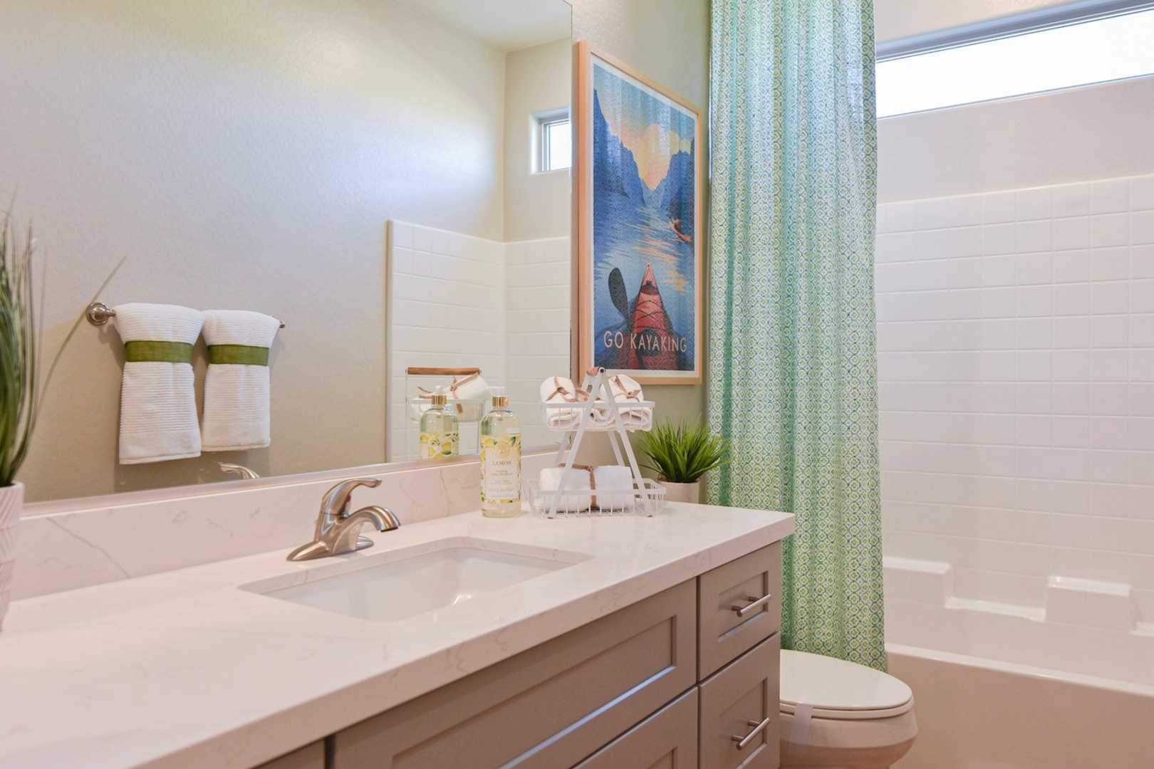 The Harmony master bathroom featuring quartz vanity, soaking tub, green accents, and potted plants by Davidson Homes