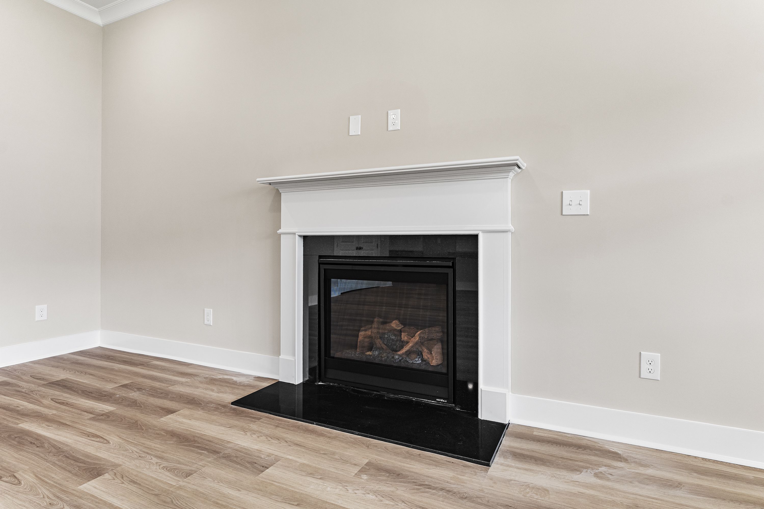 Cozy gas fireplace with white mantel in The Oxford A living room, beige walls, hardwood floors, Evermore Homes design