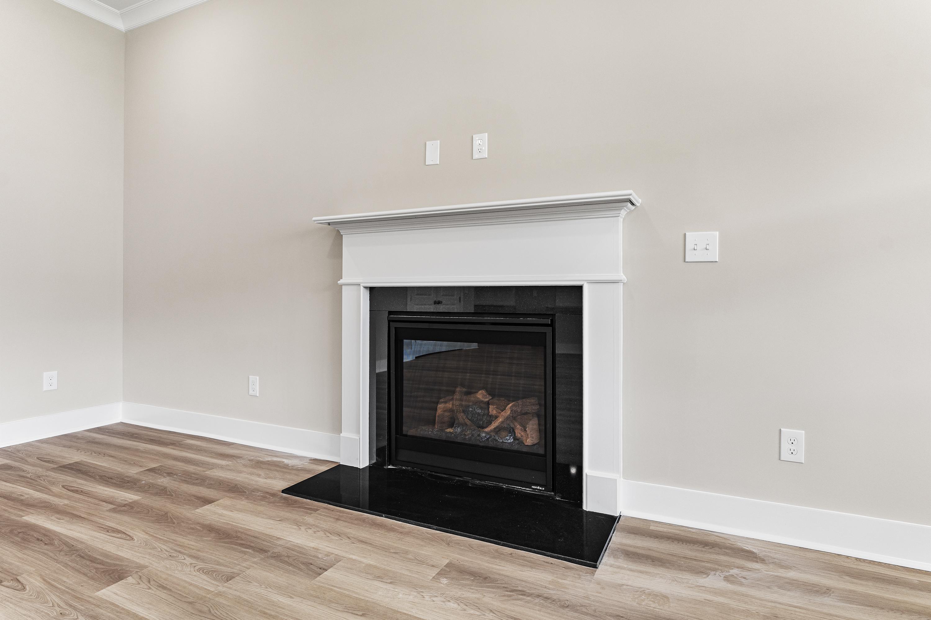 Cozy gas fireplace with white mantel in The Oxford A living room, beige walls, hardwood floors, Evermore Homes design