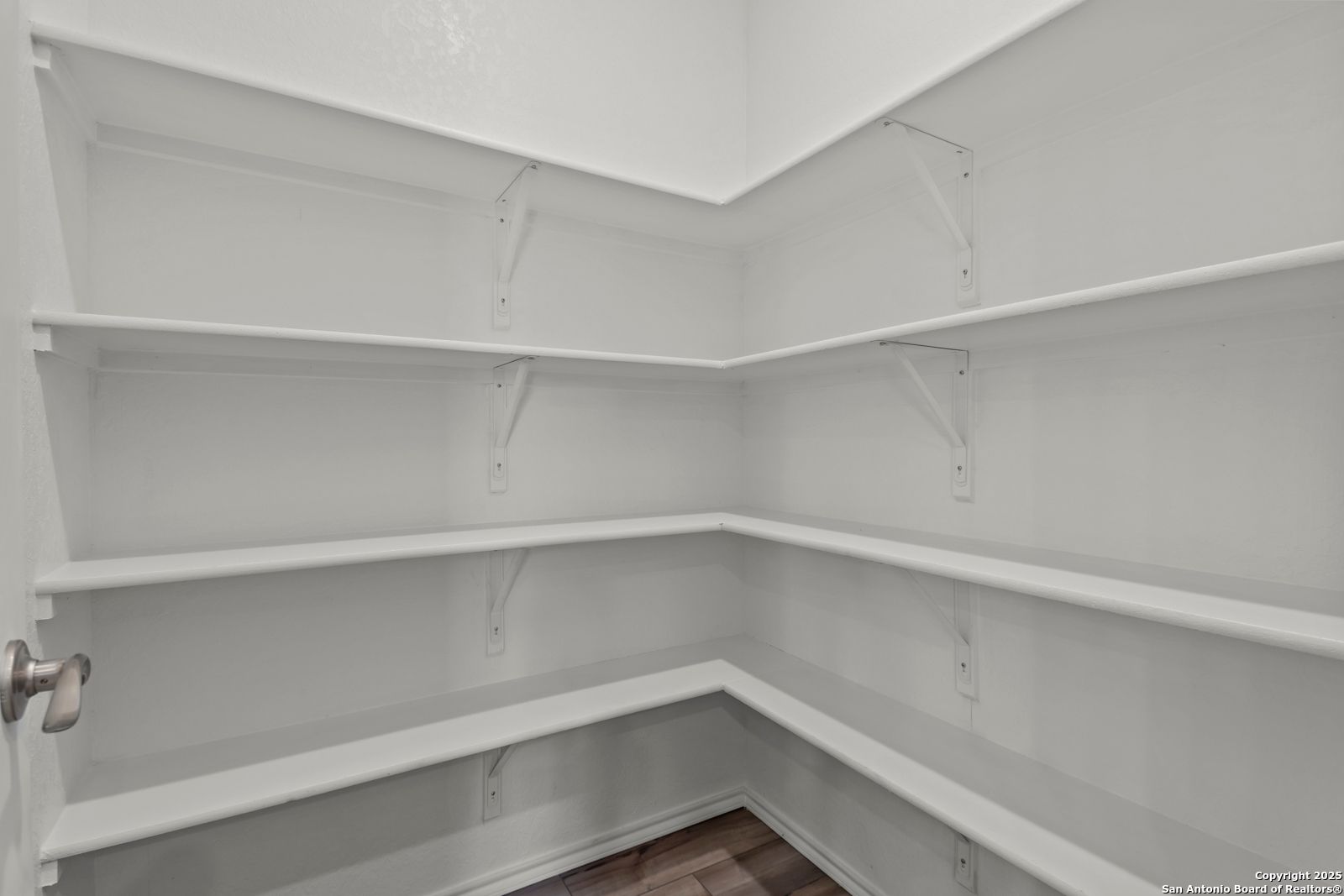 Spacious walk-in pantry with white corner shelves and hardwood floor in The Collin B 3-bedroom home, Hannah Heights, Seguin, Texas